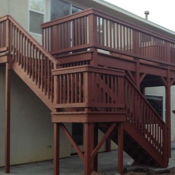 Brown wooden exterior stairs and elevated deck attached to a house on the side of a building