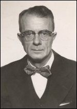 Black-and-white portrait of a man in glasses and a bow tie, facing forward with a neutral expression