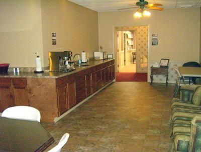 Waiting room with wooden counter, chairs, and open doorway to a hallway, lit by warm indoor lighting