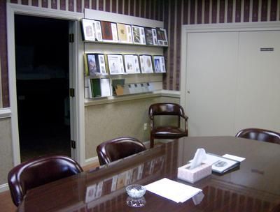 Conference room with polished table, chairs, wall brochures, and an open doorway to a dark hall.