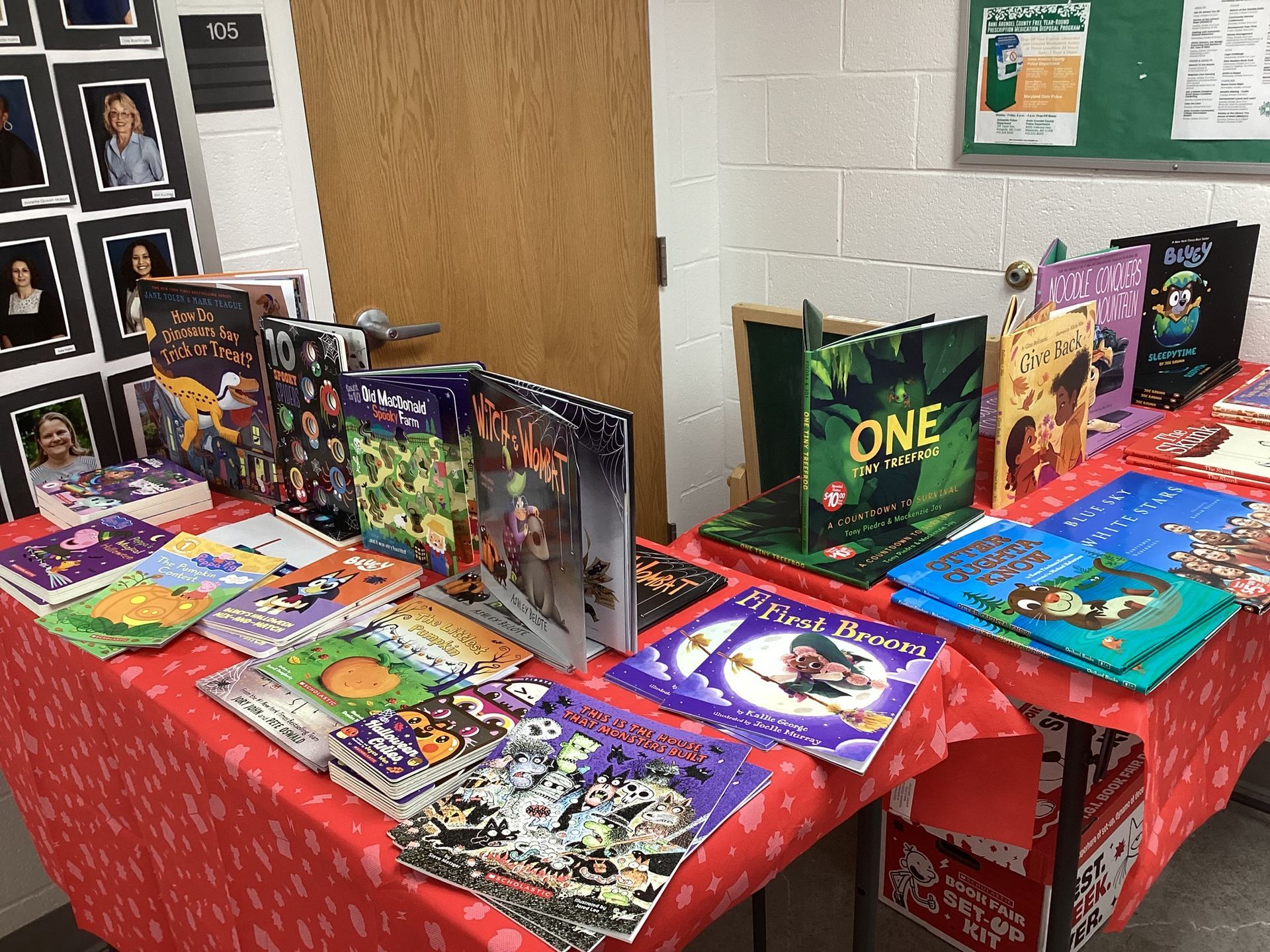 A table covered in a red cloth with books on display, likely for sale. Several are open, showcasing colorful illustrations.