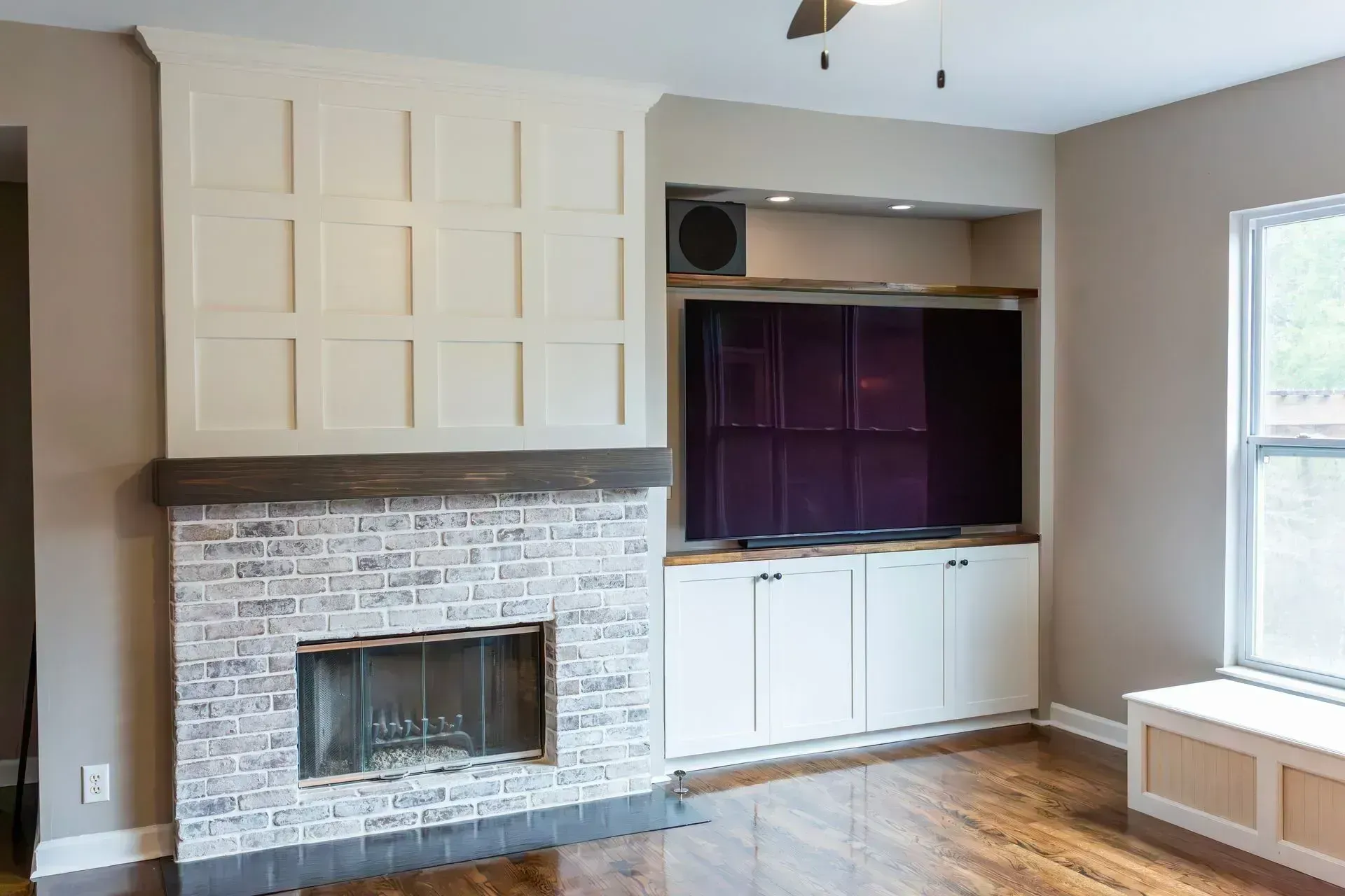 Living room with stone fireplace, built-in cabinets, and a window seat by a bright window