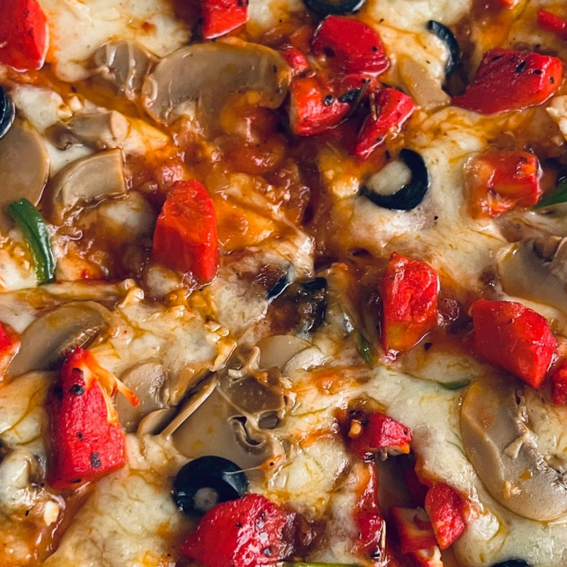 Close-up of a pizza topped with melted cheese, red bell peppers, sliced mushrooms, and black olives.