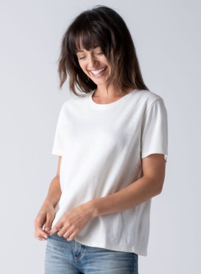 a woman wearing a white t-shirt and jeans is smiling .