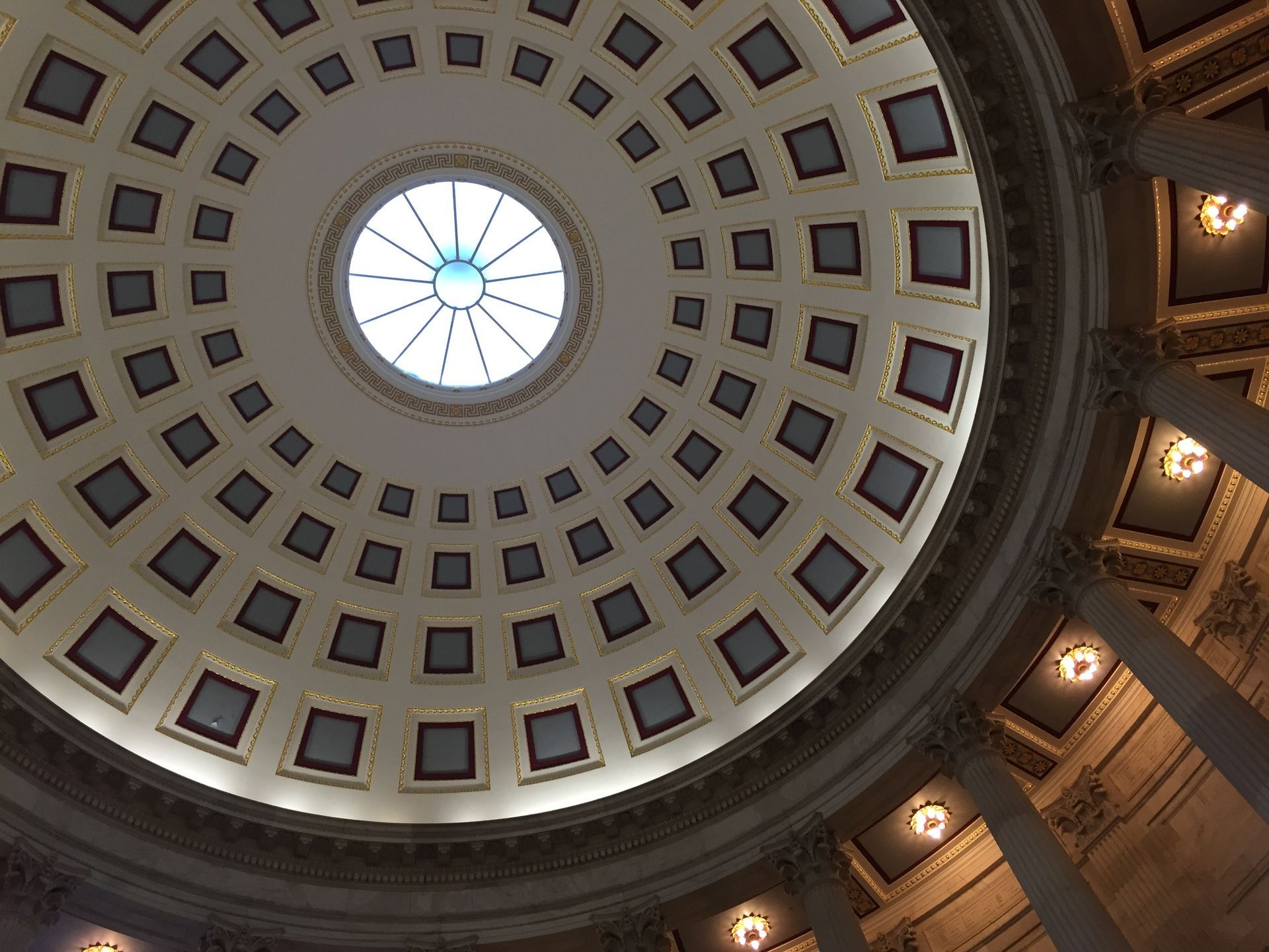 Dome ceiling with skylight, surrounded by square coffers and architectural details.