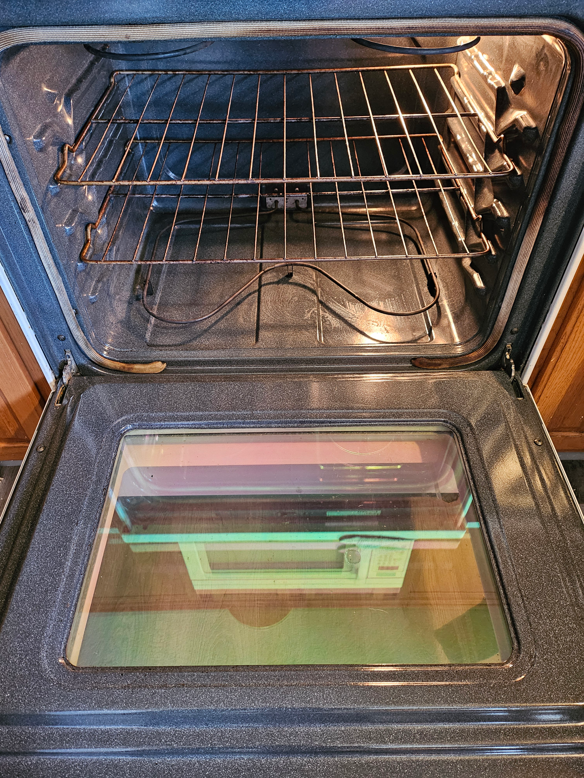 The inside of an oven with the door open and a glass door.