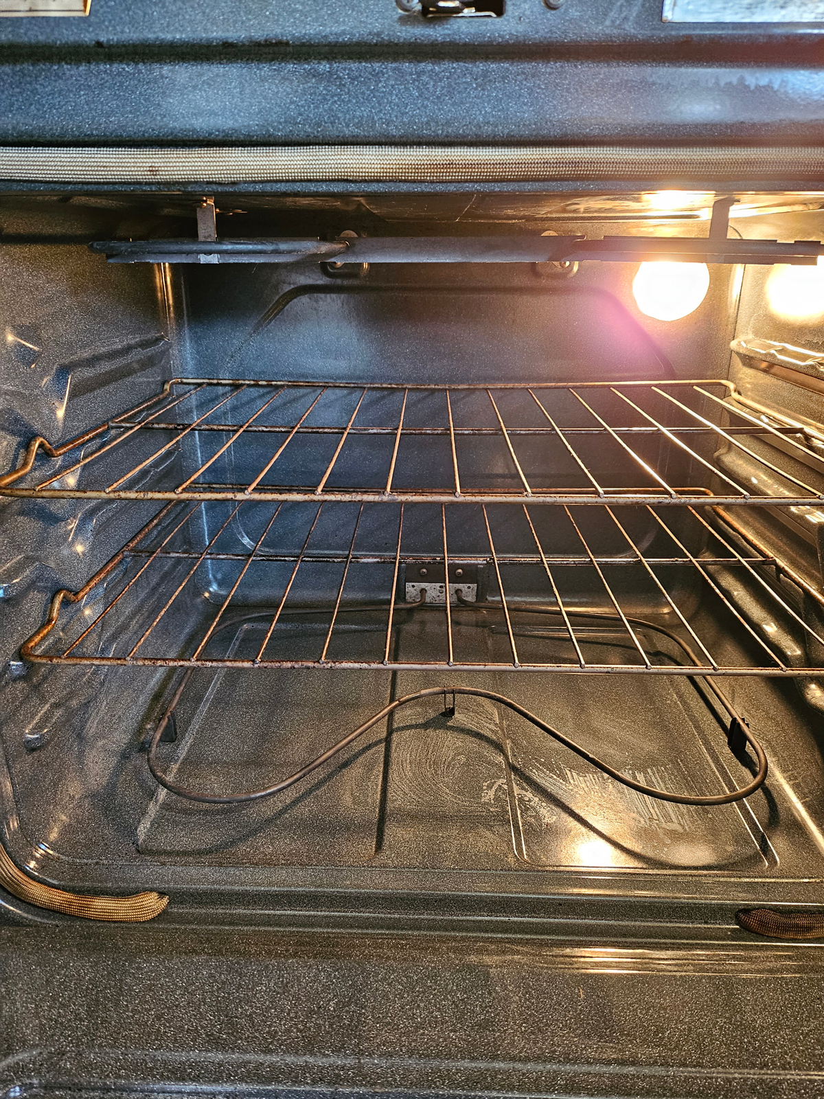 The inside of an empty oven with a light on.
