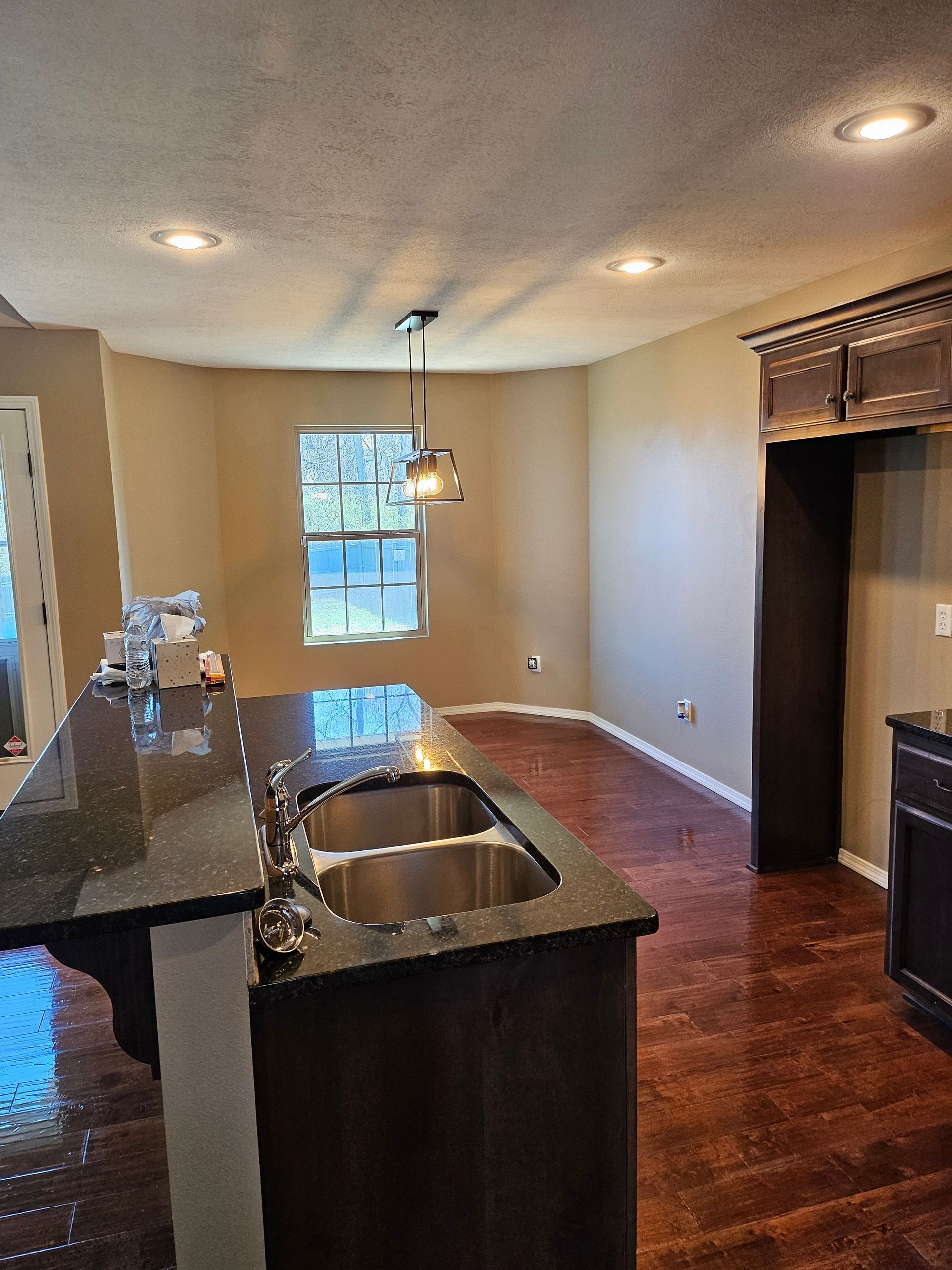 A kitchen with two sinks , granite counter tops , hardwood floors and a window.