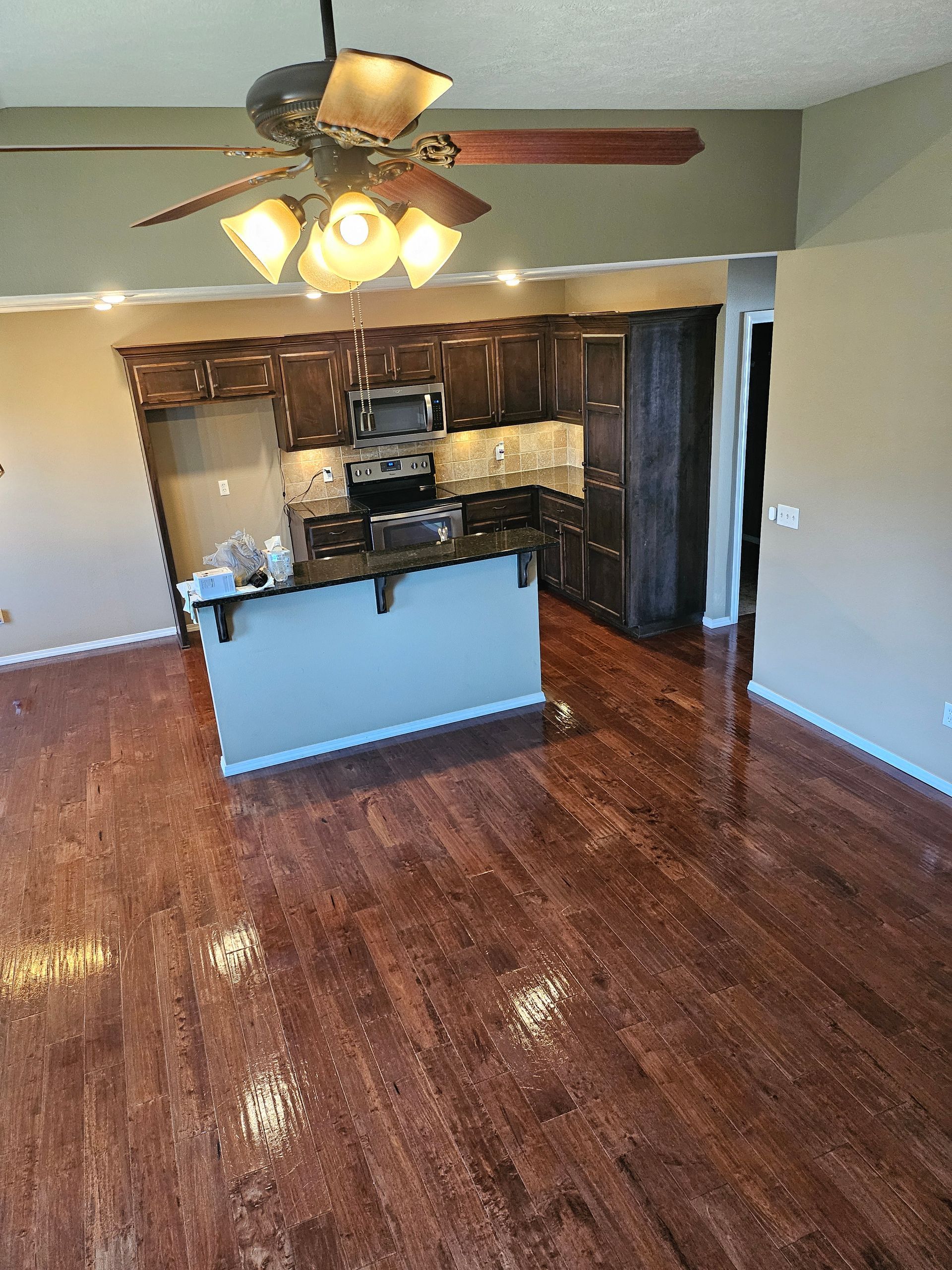 A kitchen with hardwood floors and a ceiling fan
