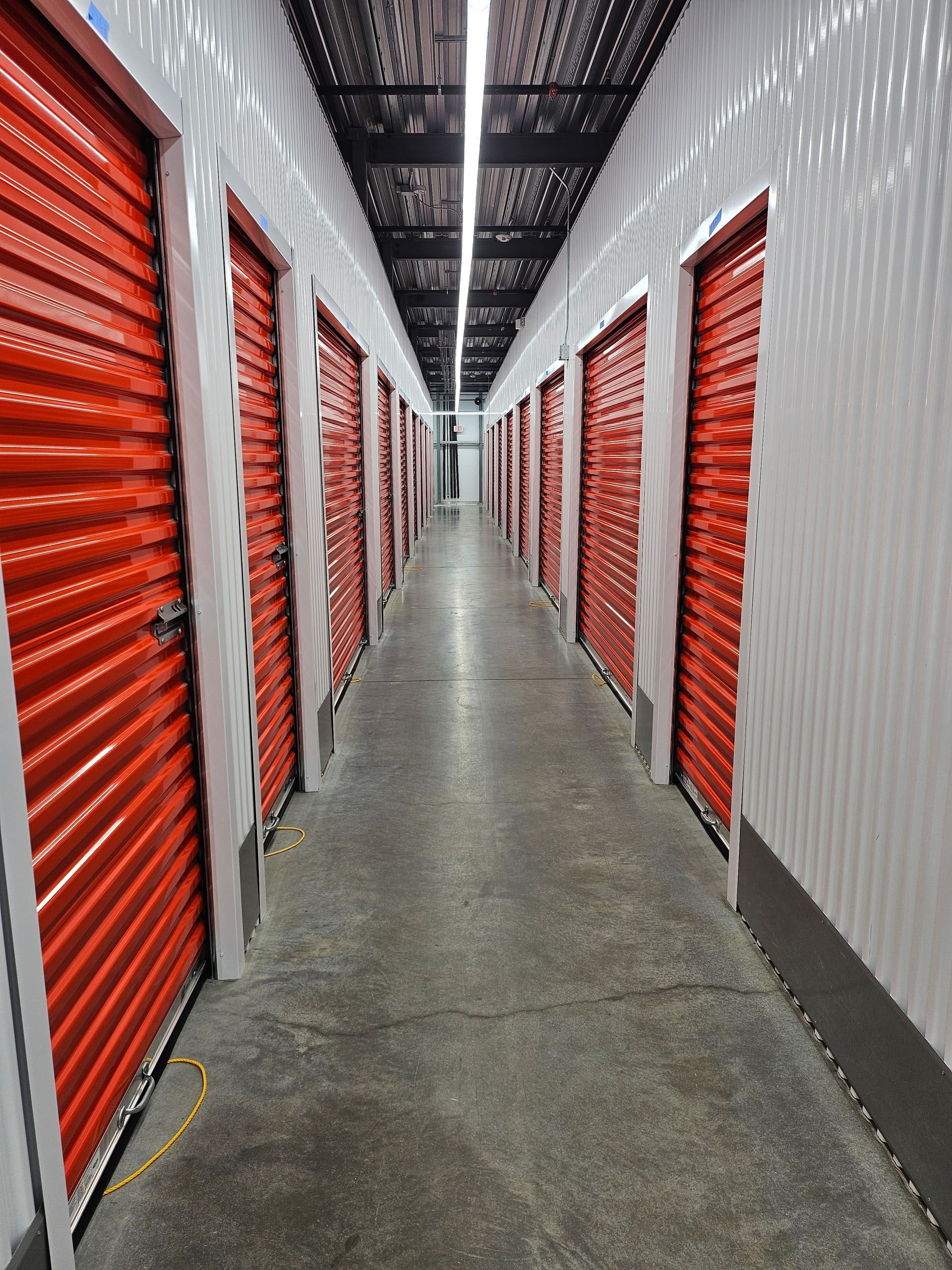 A long hallway with red doors in a storage facility.