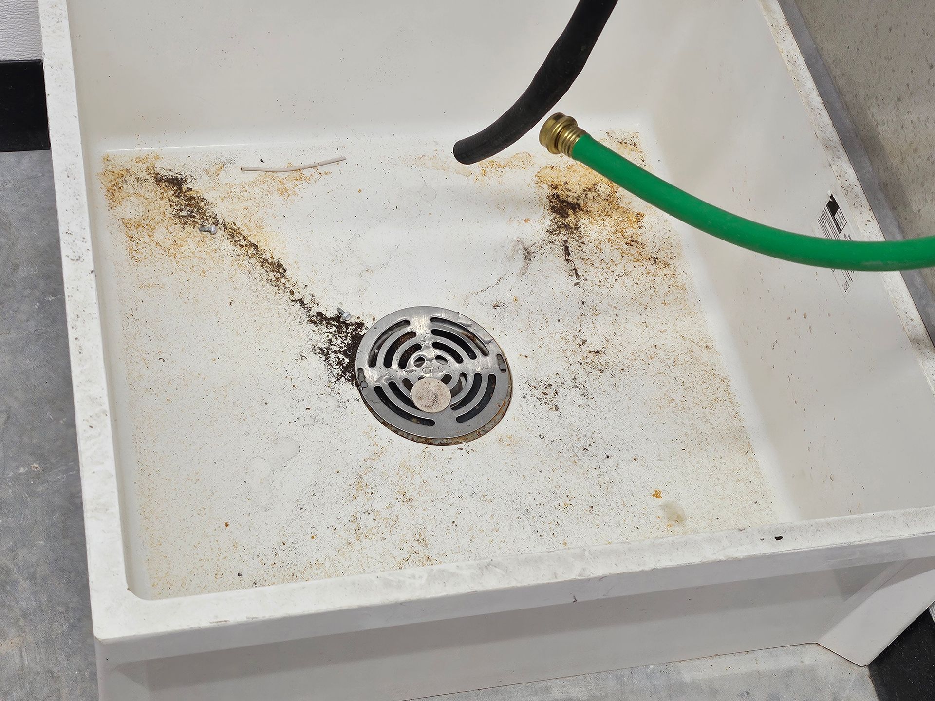 A white sink with a green hose attached to it