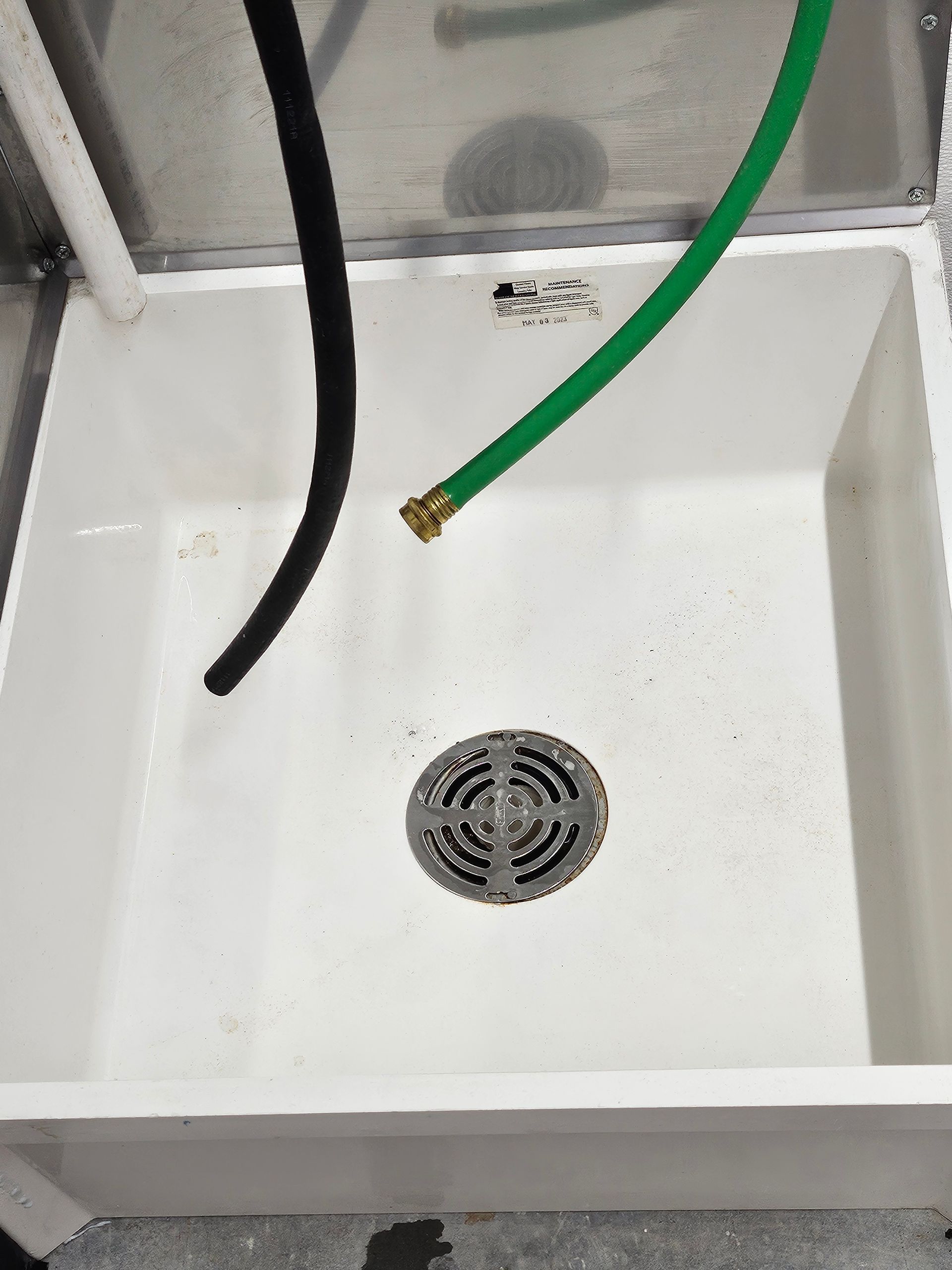 A white sink with a green hose coming out of it