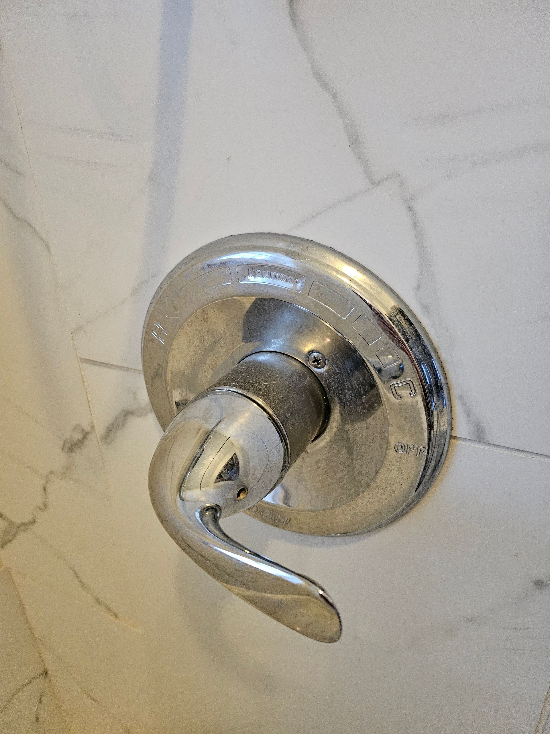 A close up of a shower head on a tiled wall.