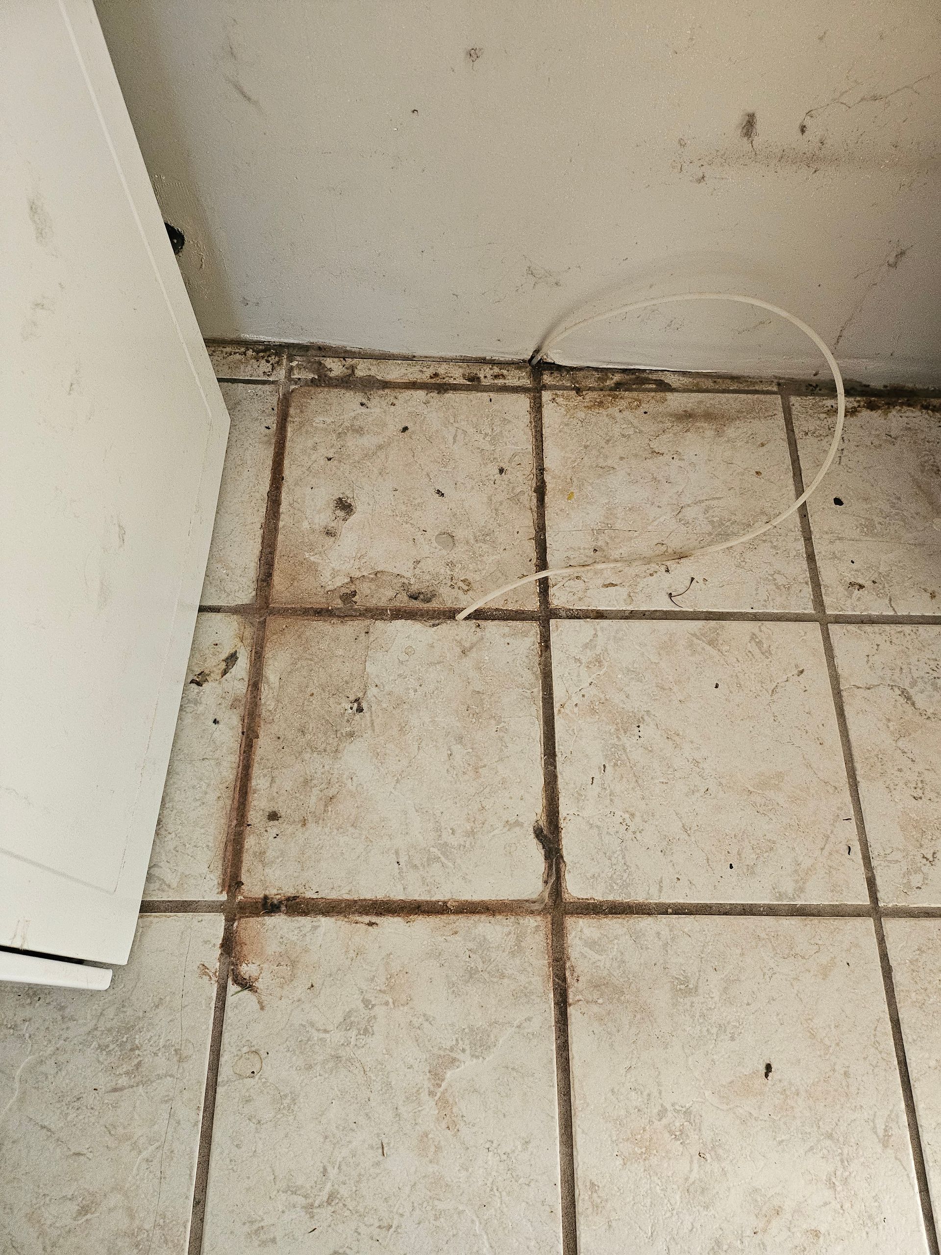 A dirty tile floor with a white door in the background