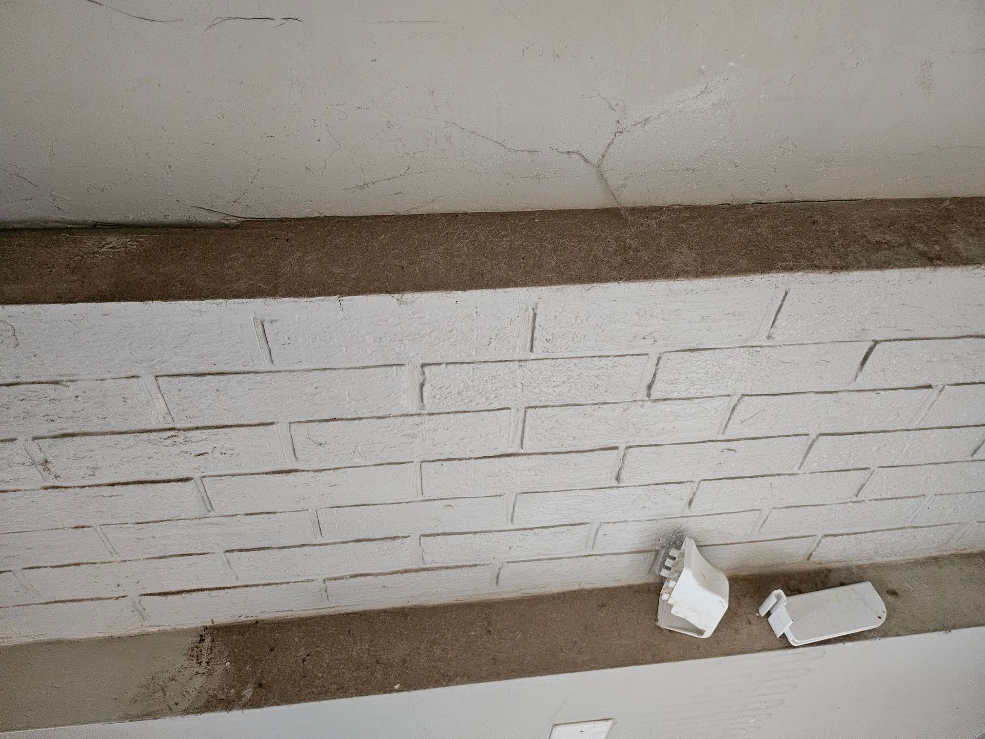 A white brick wall with a few pieces of styrofoam on it