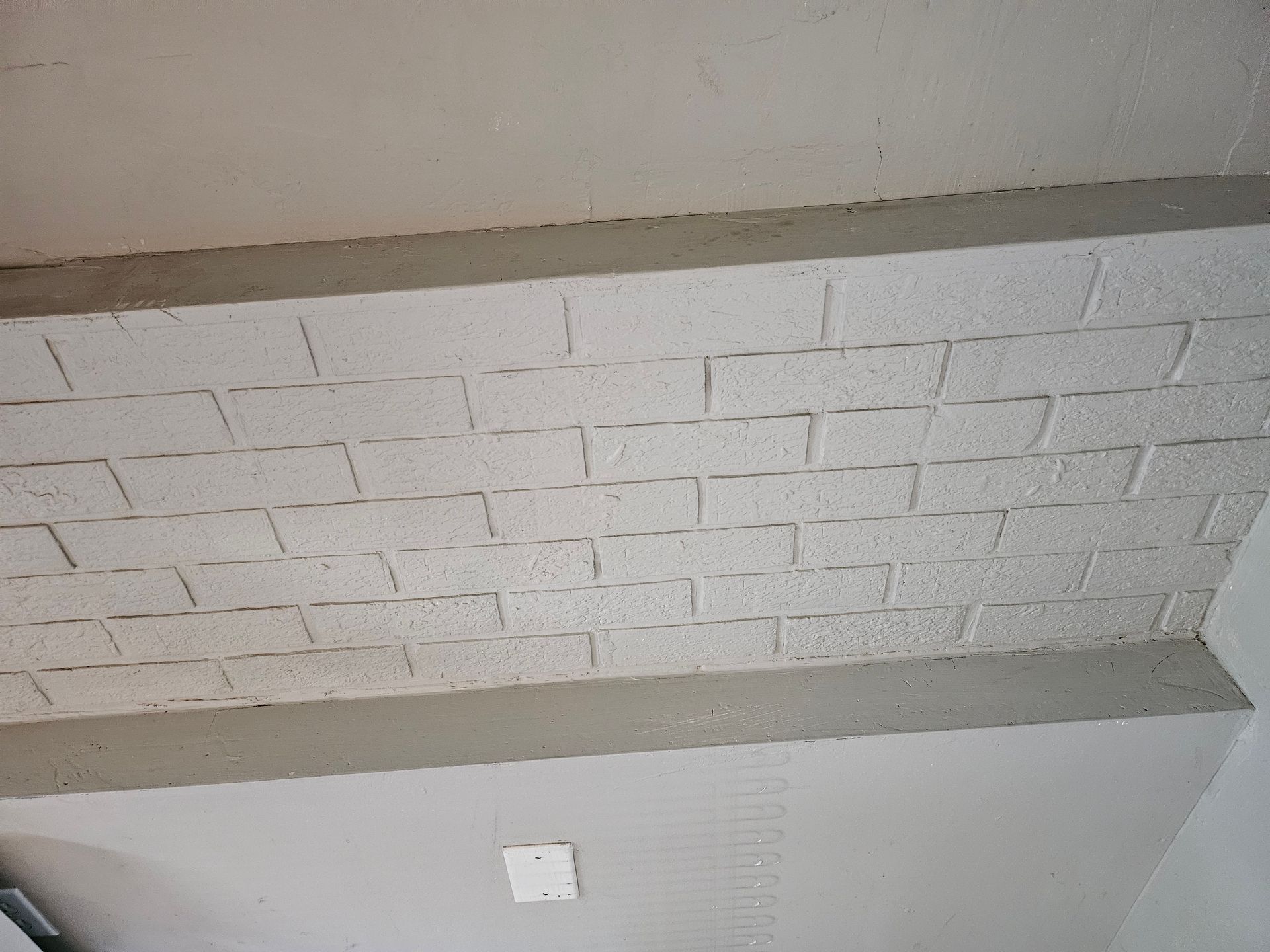 A ceiling with white bricks and concrete beams in a room.