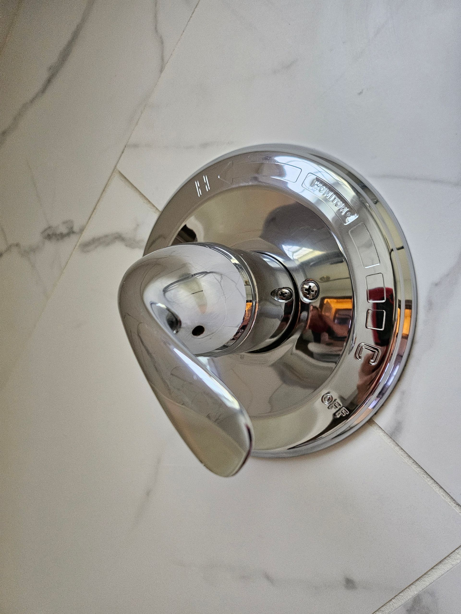 A close up of a chrome shower head on a tiled floor.