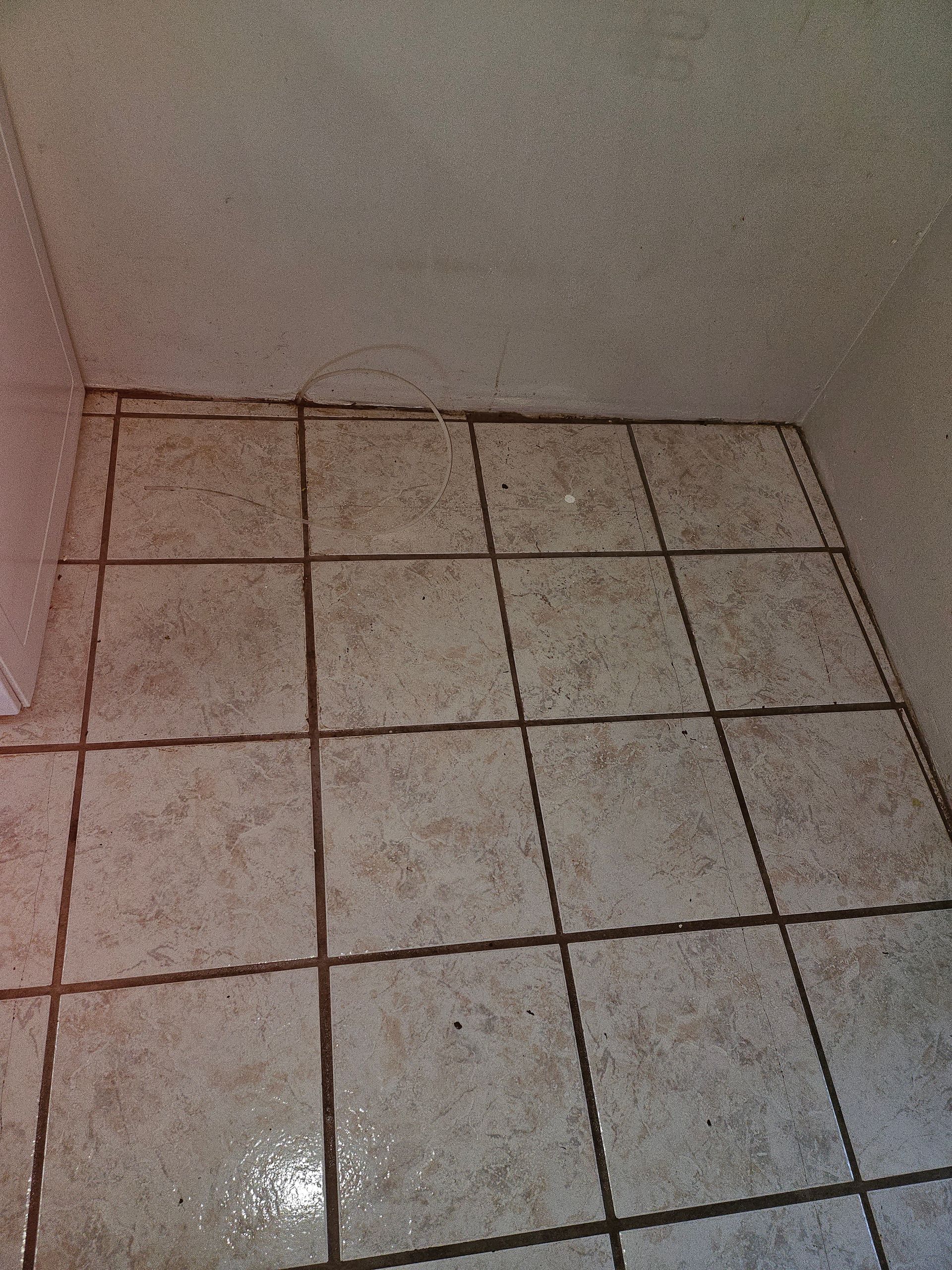 A tiled floor in a room with a white wall.