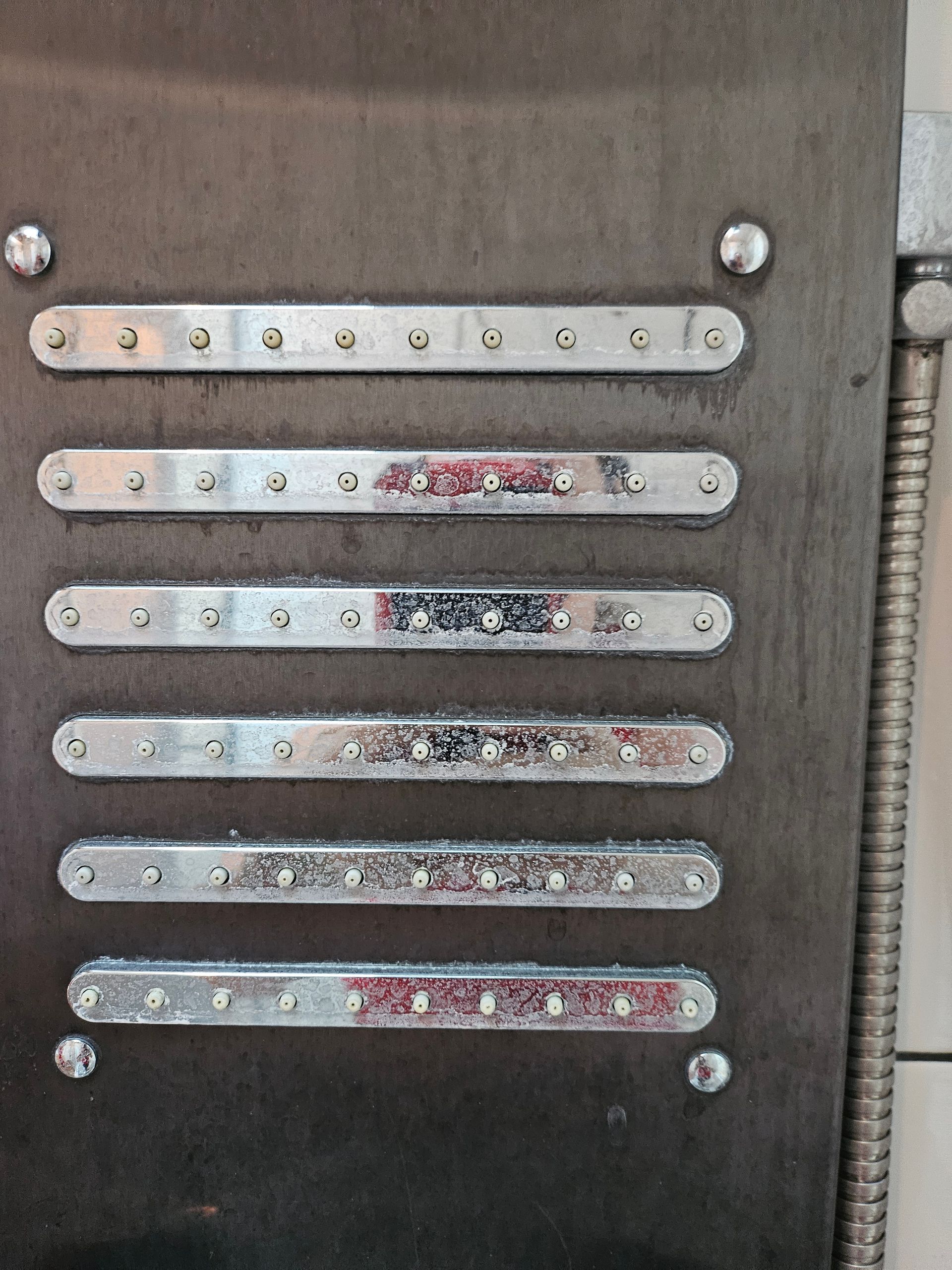 A row of metal bars are lined up on a wall.