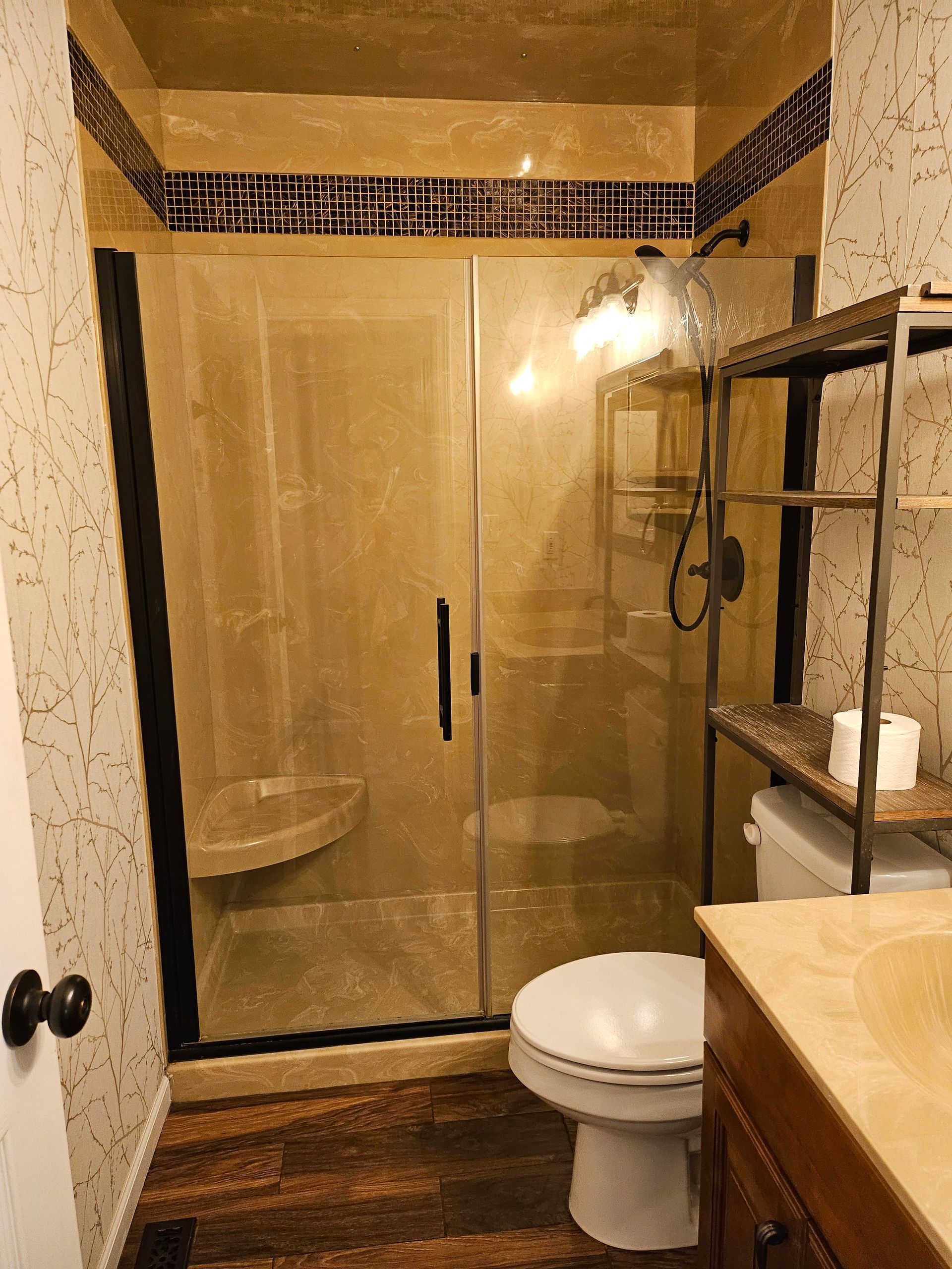 A bathroom with a toilet , sink , shower and glass door.