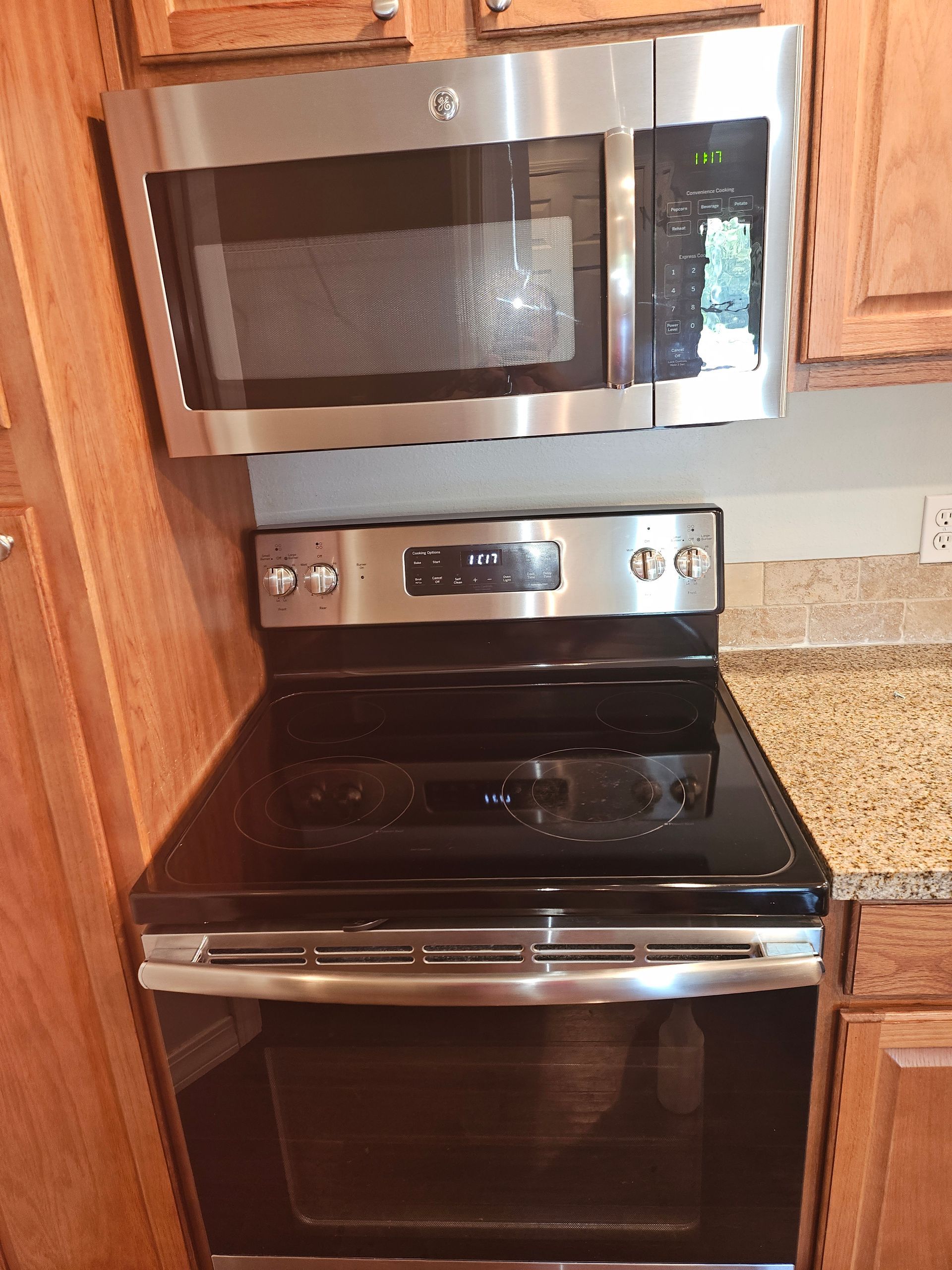 A black stove top oven with a stainless steel microwave above it.