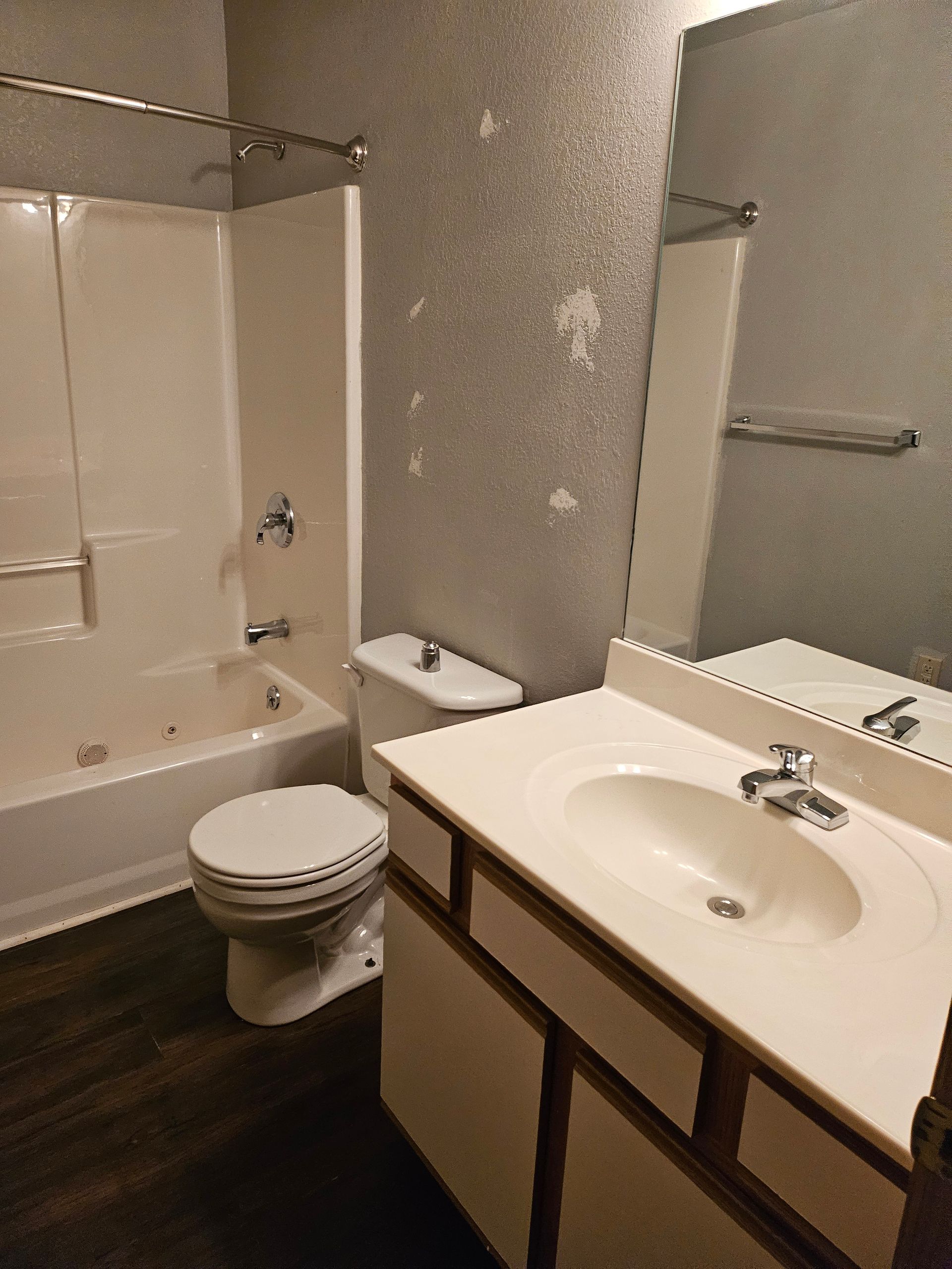 A bathroom with a toilet , sink , bathtub and mirror.