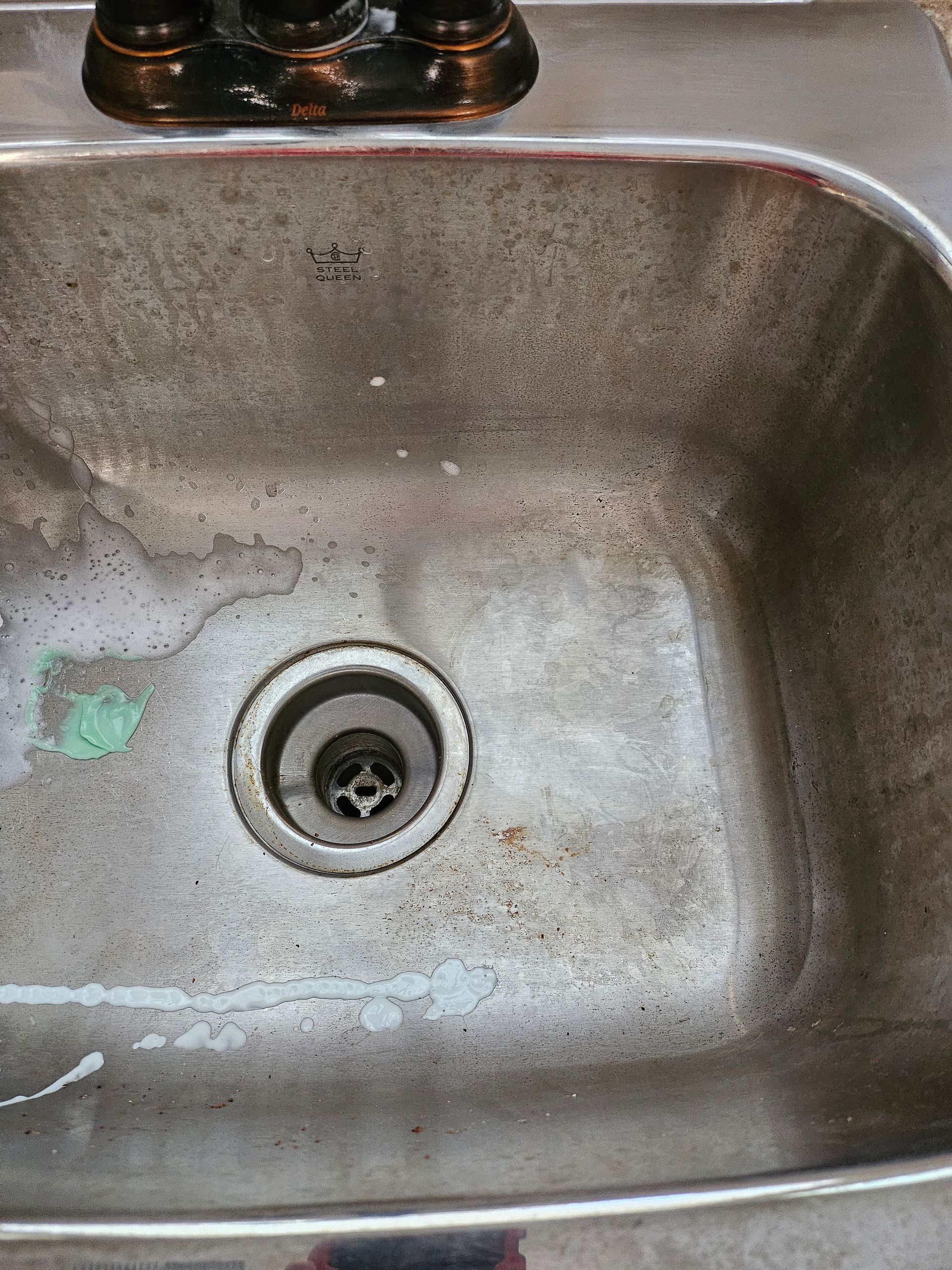 A dirty stainless steel sink with a drain hole