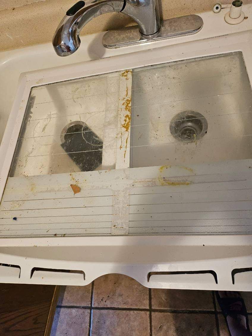A dirty kitchen sink with a faucet and drain.