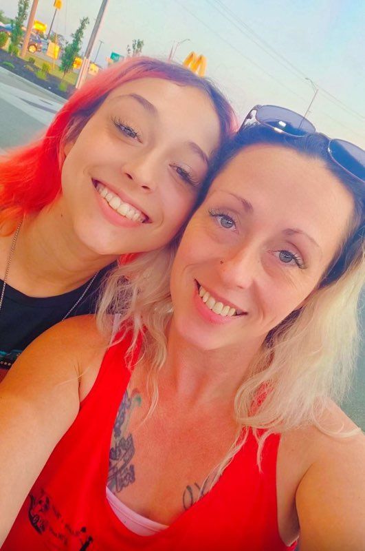 Two women are posing for a picture together and smiling for the camera.