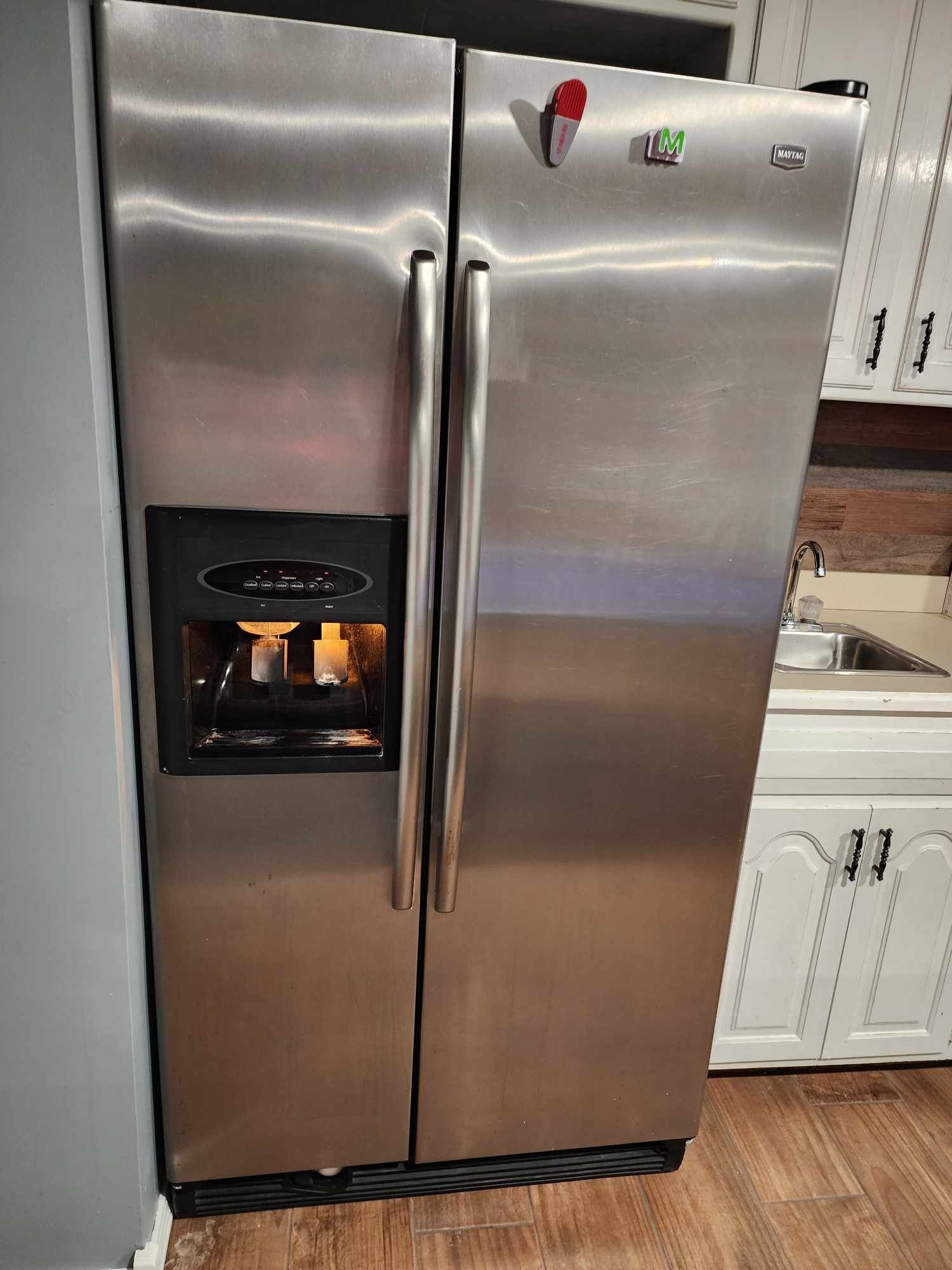 A stainless steel refrigerator is sitting in a kitchen next to a sink.