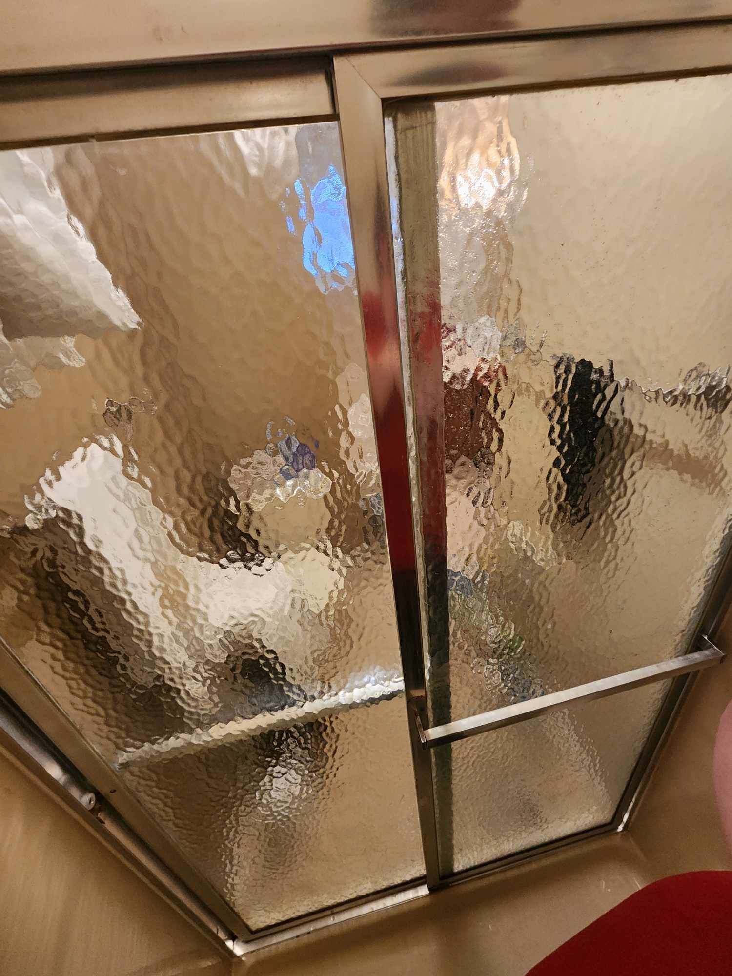 A close up of a glass shower door in a bathroom.