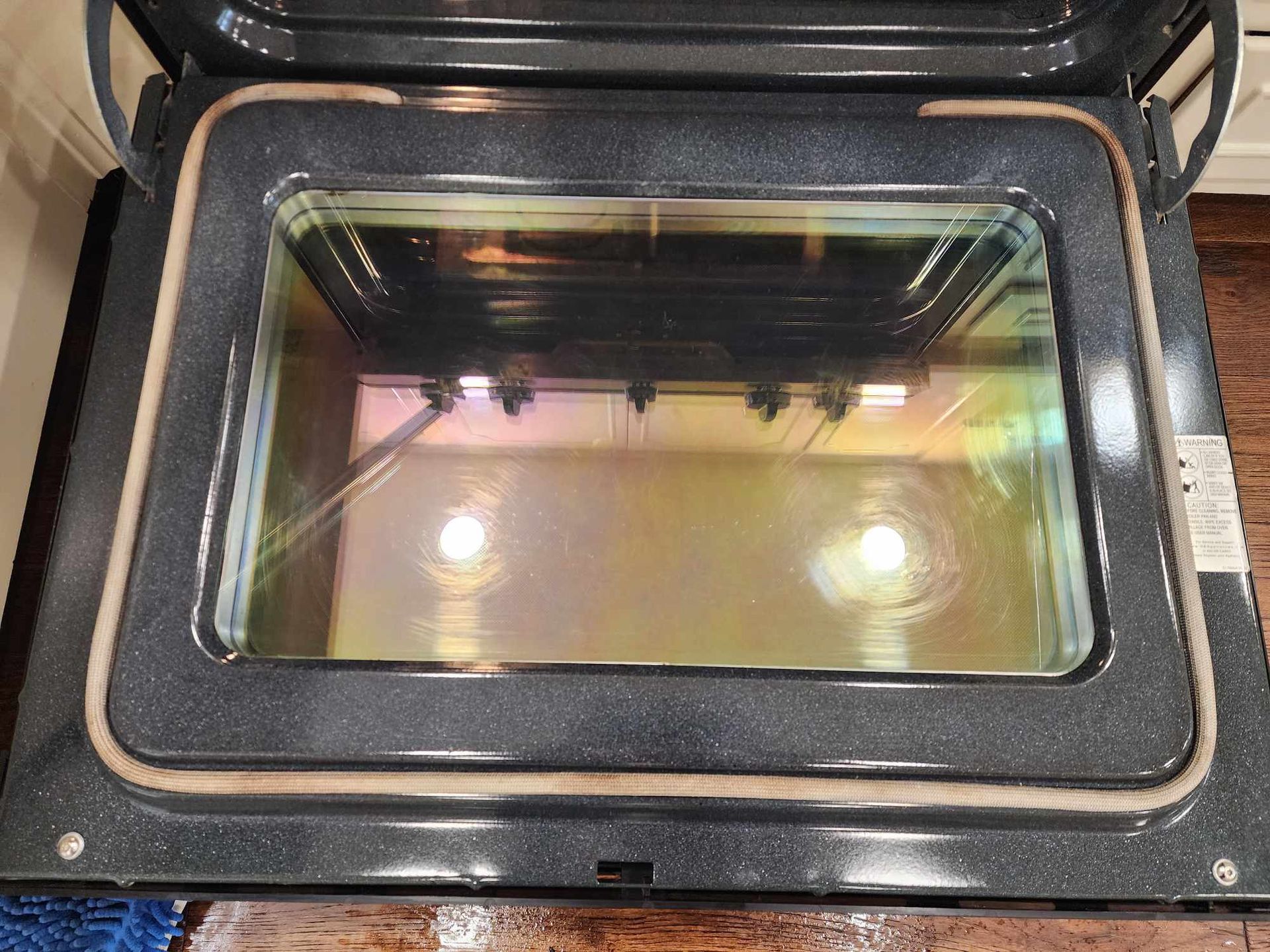 The inside of an oven with the door open and a glass door.
