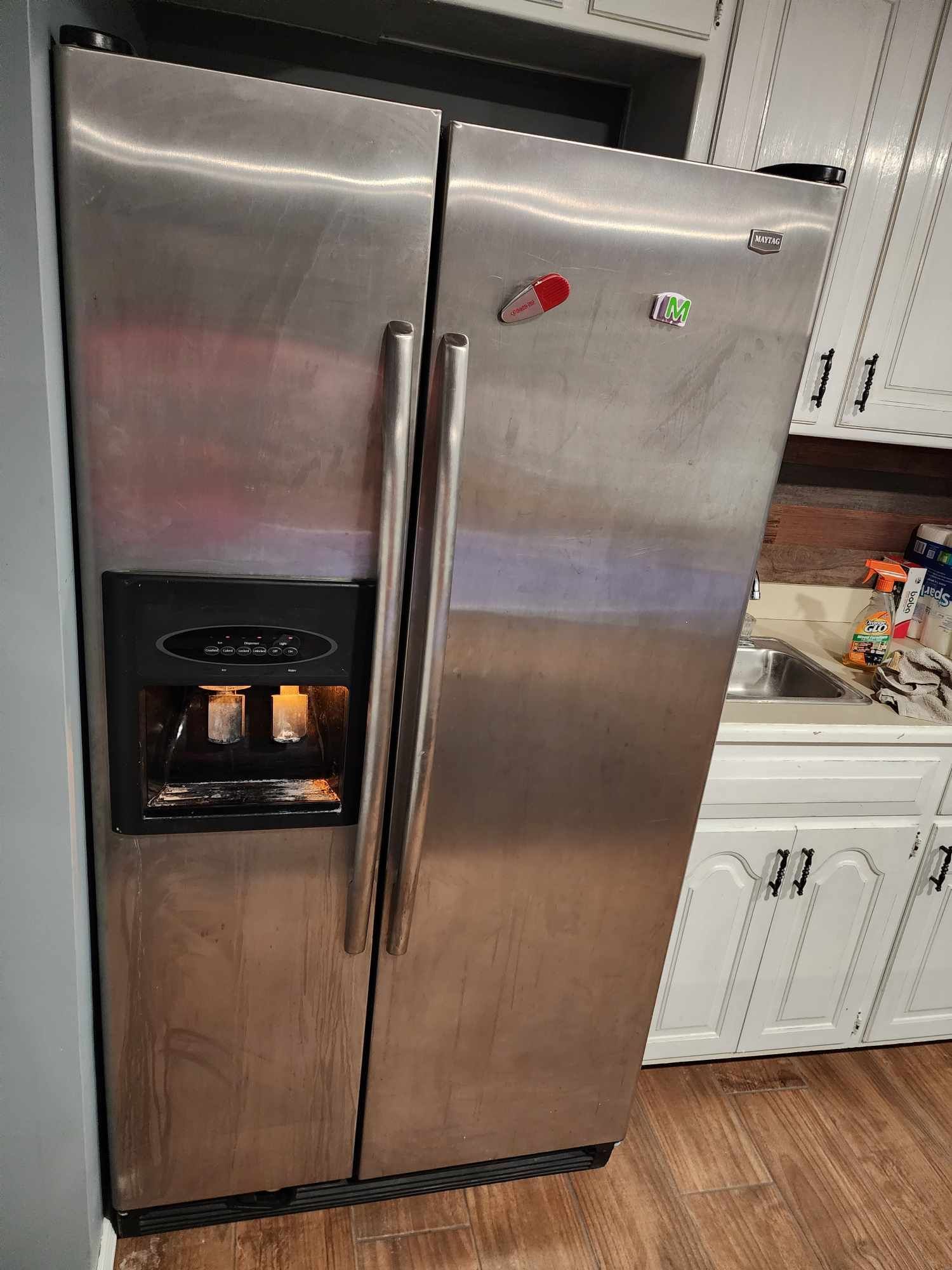 A stainless steel refrigerator is sitting in a kitchen next to a sink.