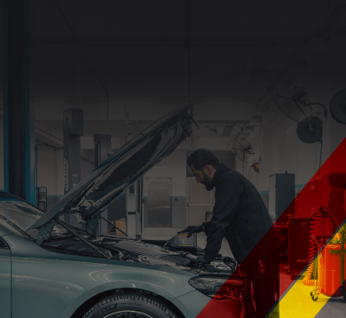 Dim auto repair shop with a car on a lift, mechanic, and red-yellow diagonal stripe on the right. | D&D Tire & Auto Center