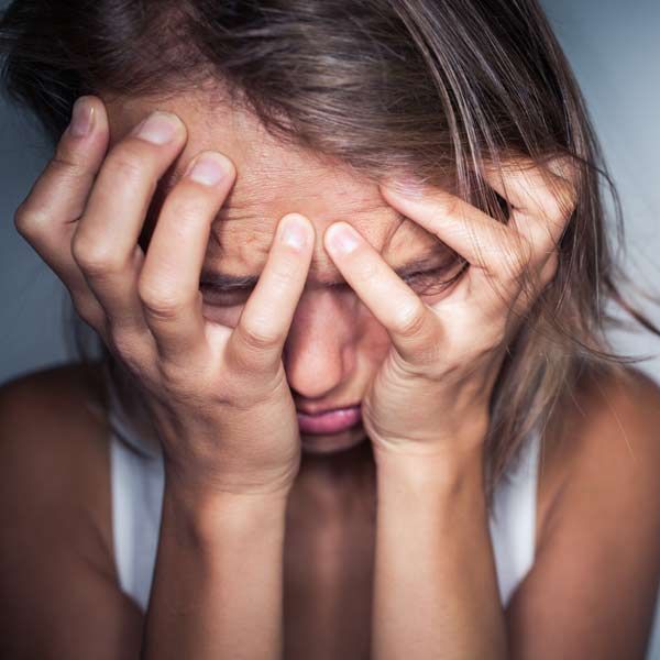 A woman is covering her face with her hands representing Anxiety Treatments