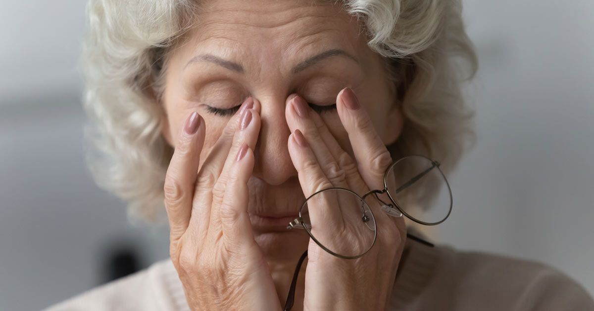 An elderly woman wearing glasses is rubbing her eyes representing  Chronic Fatigue Syndrome Treatments NYC - Dr. John Salerno