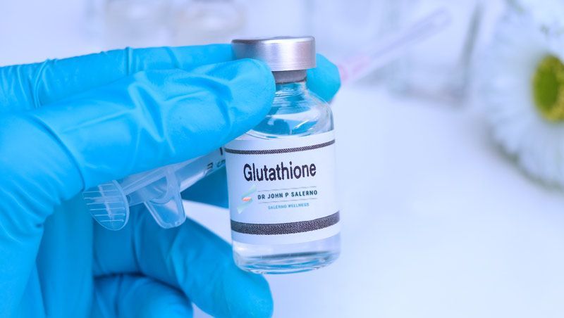 A person in a blue glove is holding a bottle of glutathione aturesAtioxdantPowerhuse