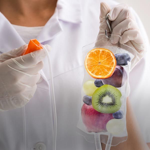 Person in lab coat holds IV bag filled with fruit.