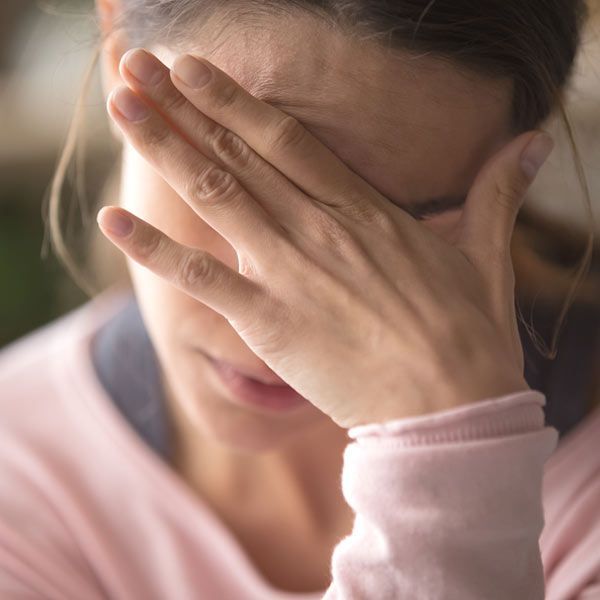 Woman with hand on forehead, looking distressed, needing Microplastics Toxicity Treatments