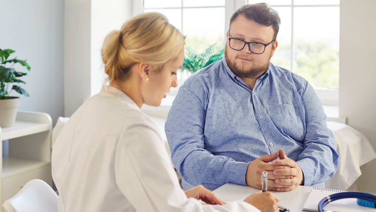 A man is completing intake forms for Obesity Treatment NYC with a nurse.