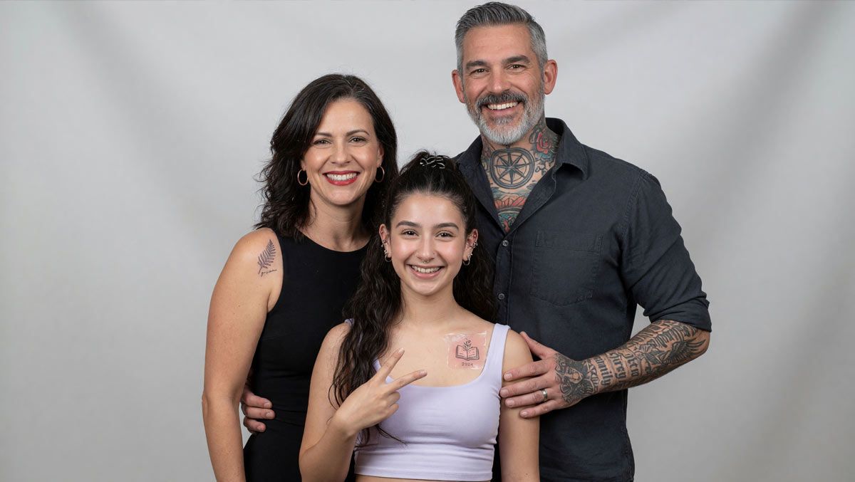 Family with tattoos smiling and posing together against a light gray backdrop