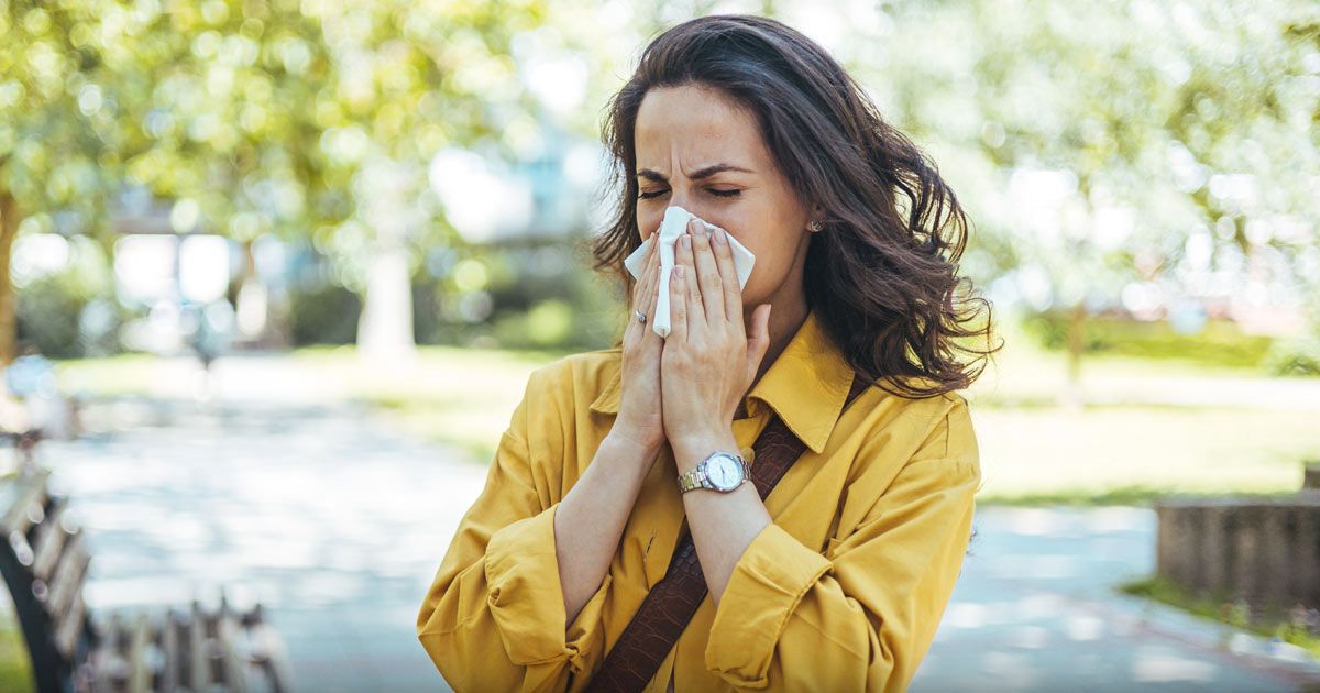 A woman is blowing her nose into a napkin what You Dont Know About Allergy Season.