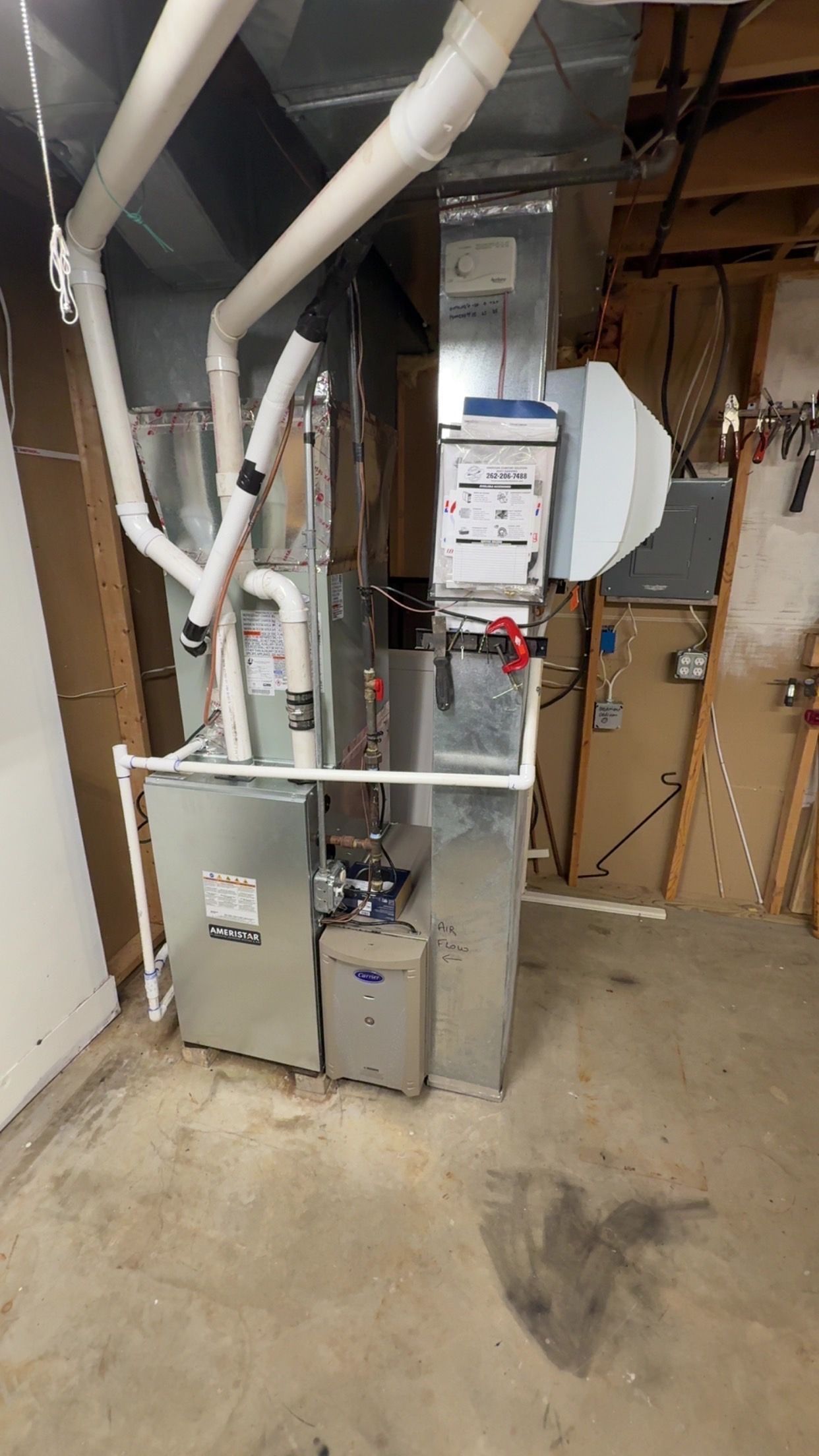 Basement HVAC furnace and ductwork with exposed pipes and service panels