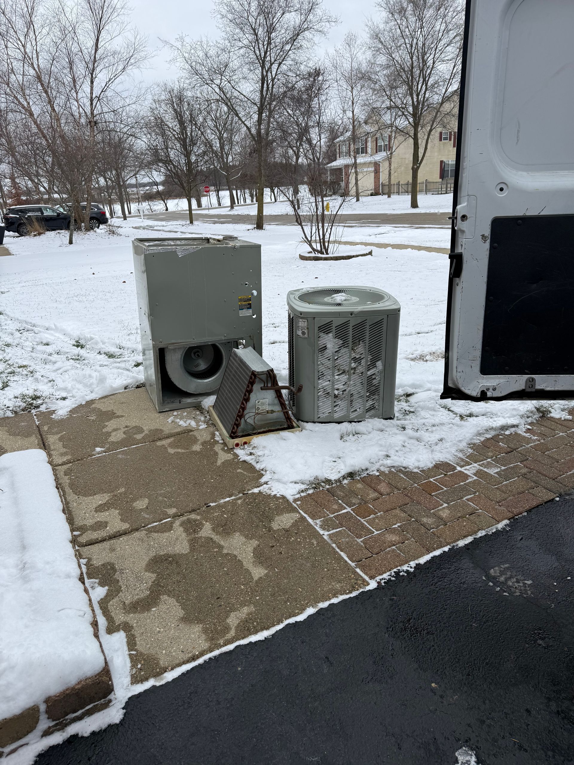 Snowy sidewalk beside two gray utility boxes and a building wall in winter.