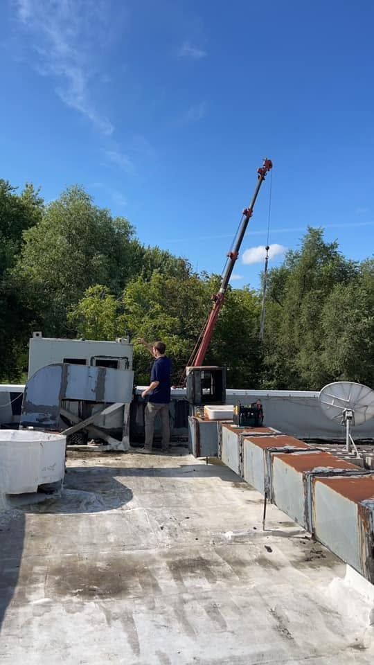 Rooftop work site with crane, equipment, and satellite dish under a blue sky
