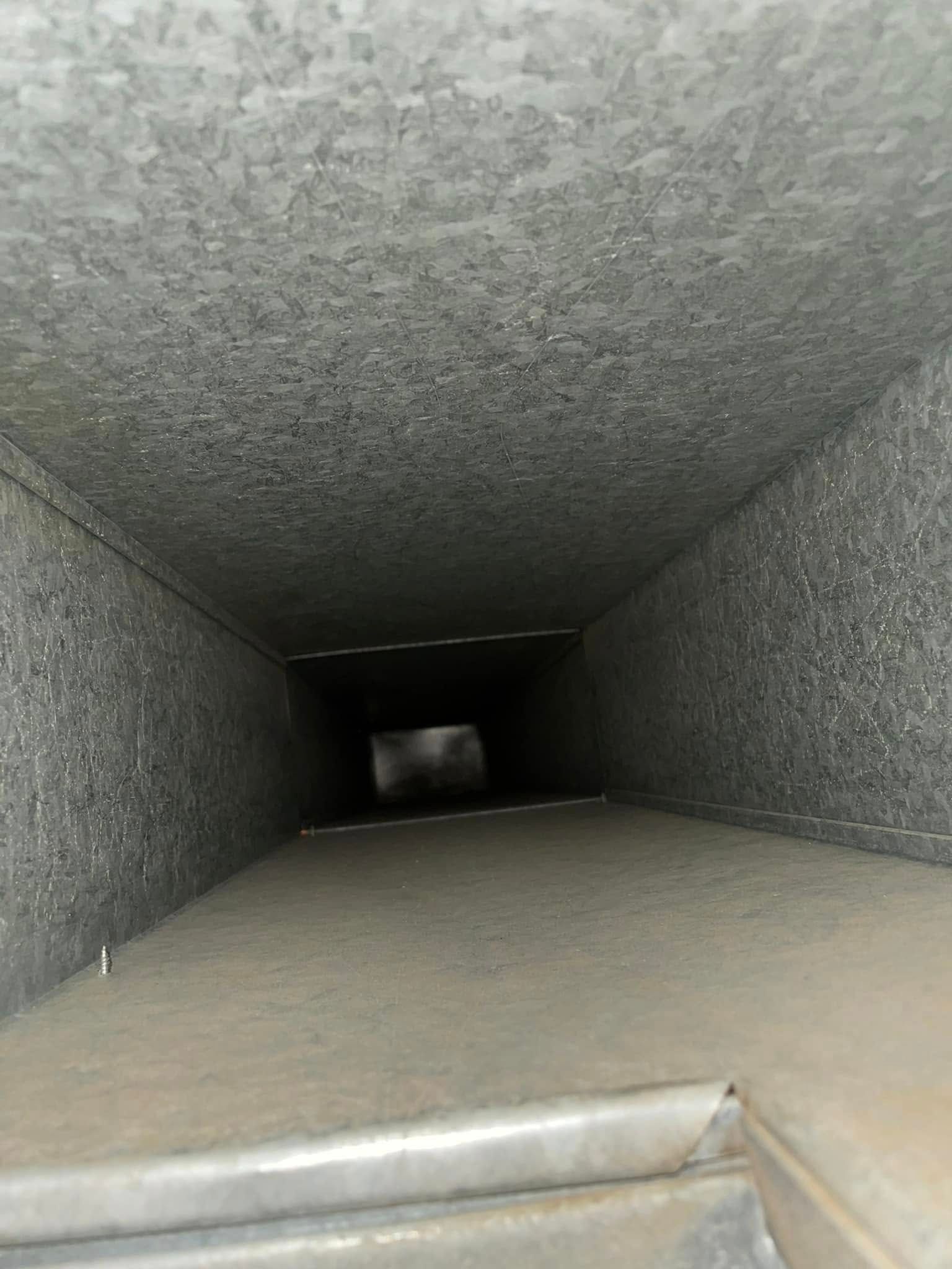Inside a square metal duct, looking down a narrow ventilation shaft.