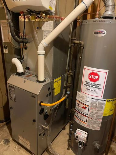 Indoor HVAC unit and water heater with connected pipes and warning labels in a utility closet