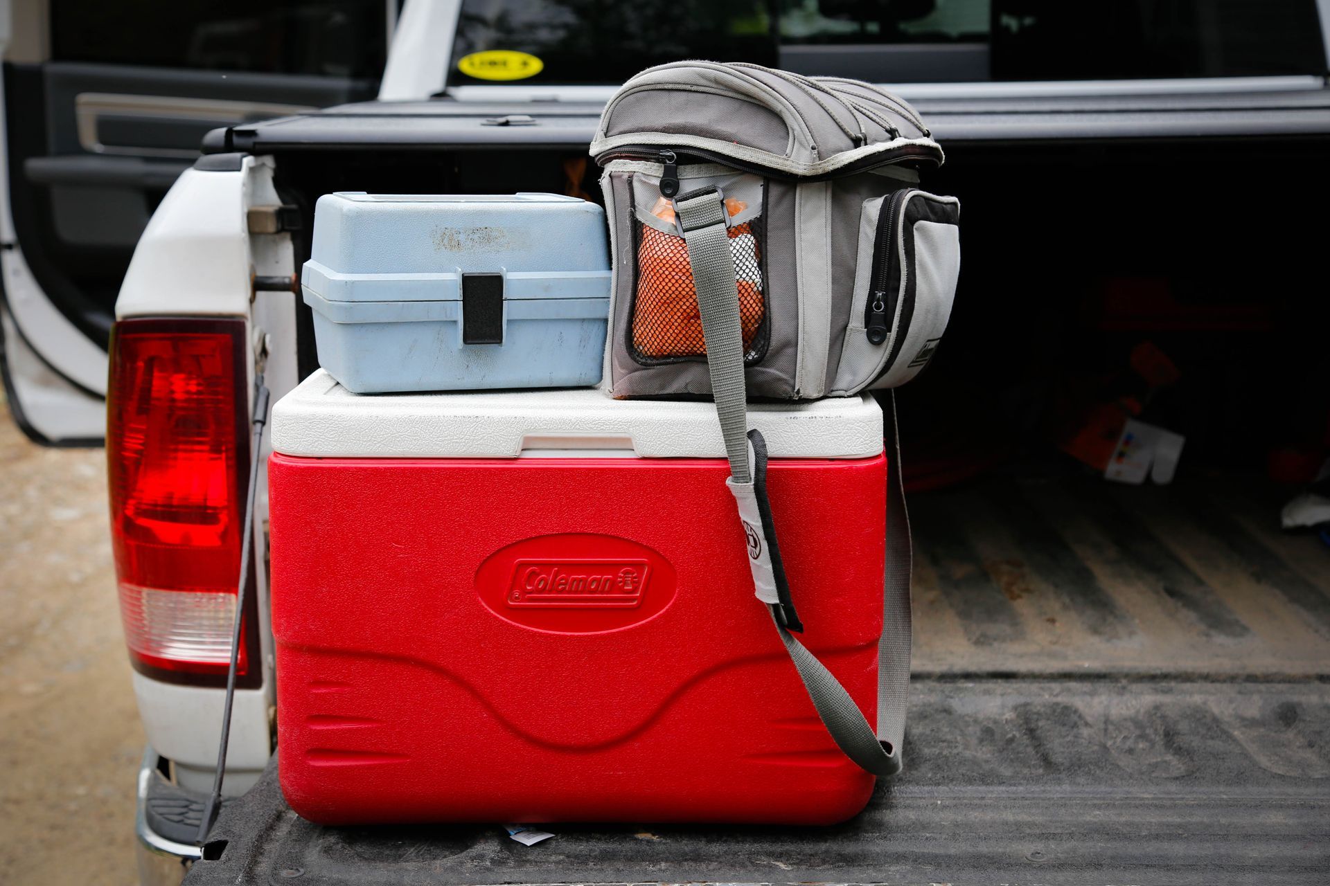 Glacière rouge remplie d'une boîte de pêche et d'un sac à lunch dans la benne du camion.