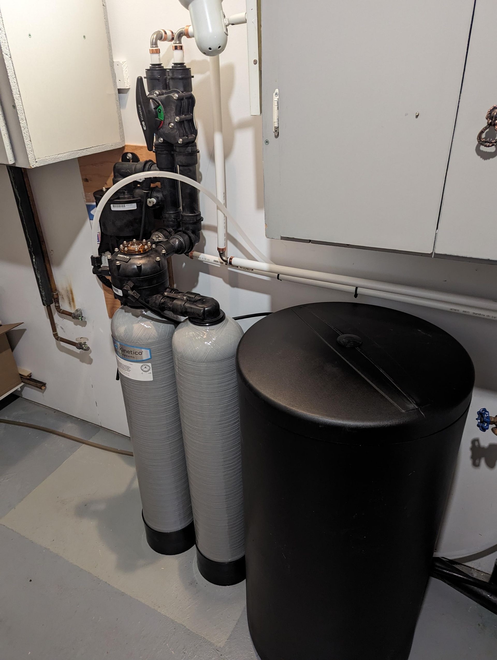 Système de filtration d'eau avec trois réservoirs et un réservoir de sel noir dans une buanderie.
