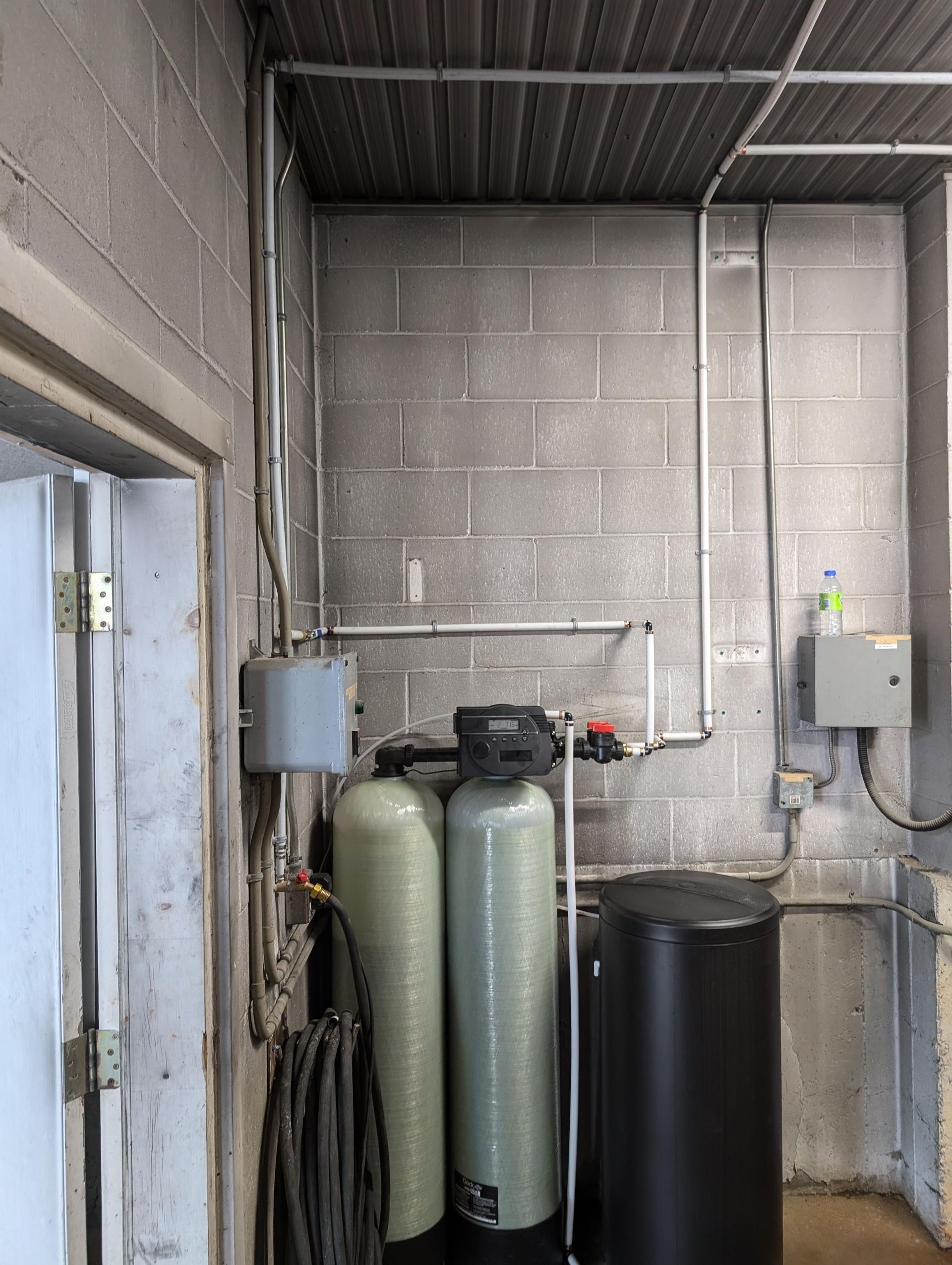 Système de filtration d'eau et conduit électrique sur un mur en blocs de béton, milieu industriel.